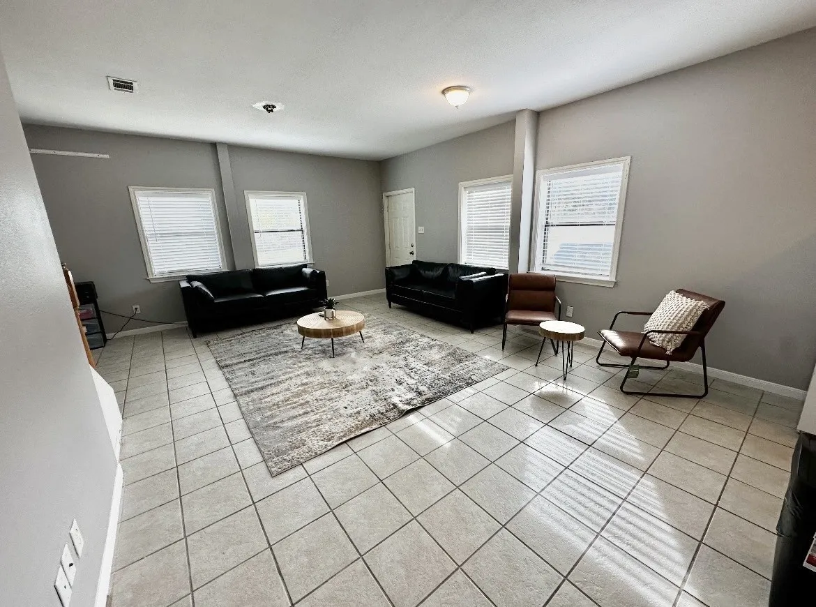 Spacious interior featuring tile flooring, multiple windows with blinds, and light gray wall finishes