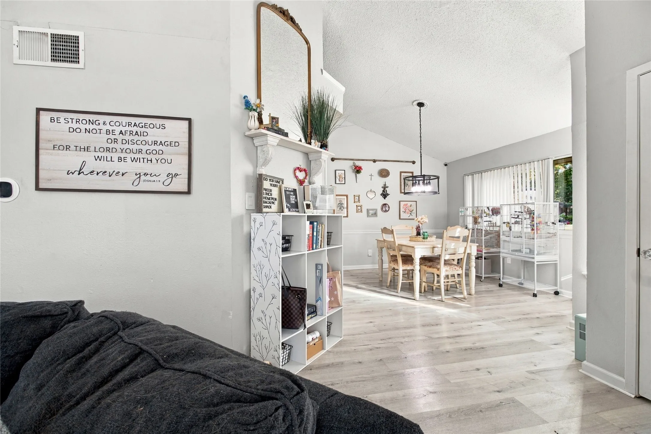 Light-toned wood-finish flooring throughout, vaulted ceiling, and dining area with a modern chandelier