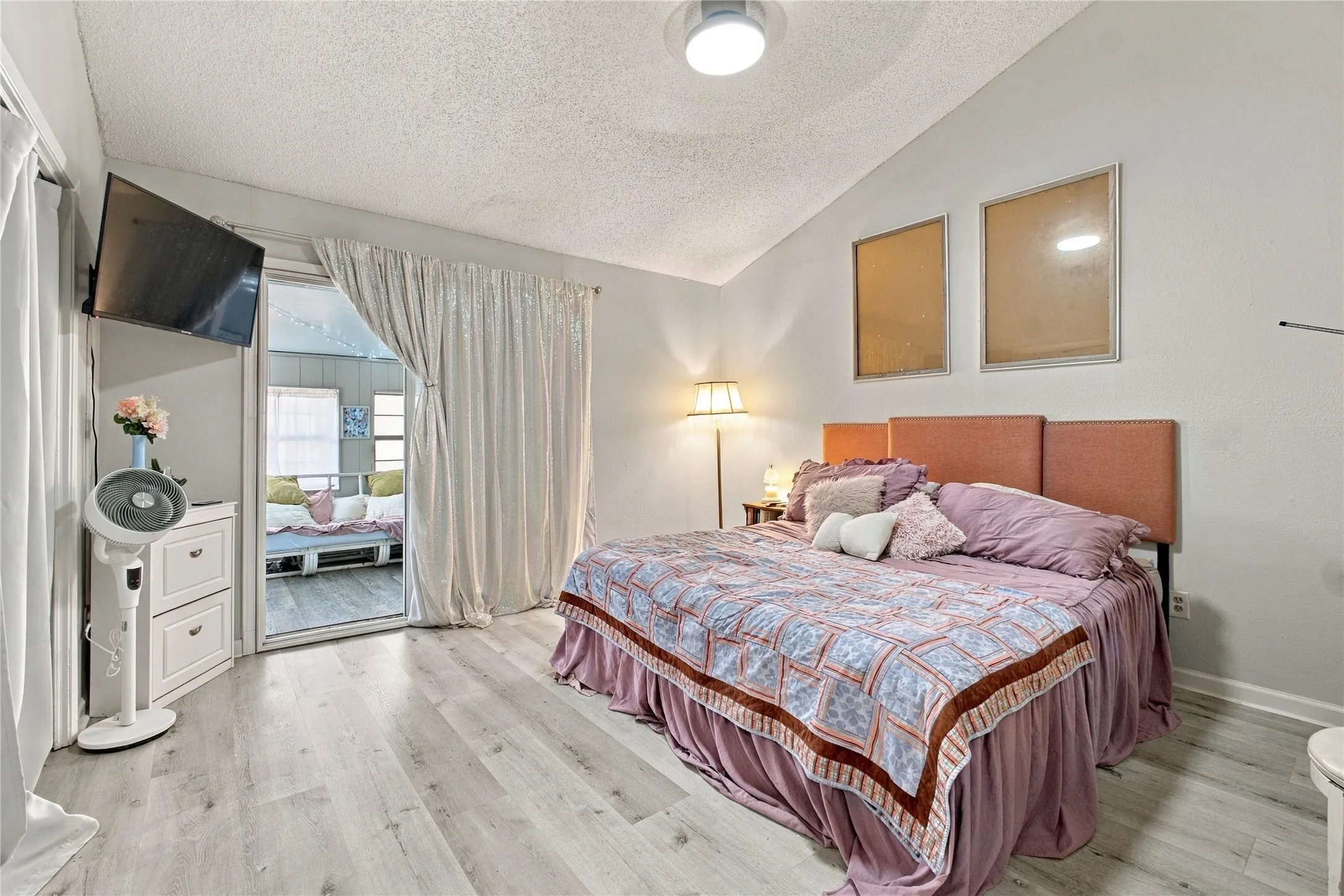 Vaulted ceiling, wood-finish flooring, sliding glass door, recessed lighting, and wall-mounted television