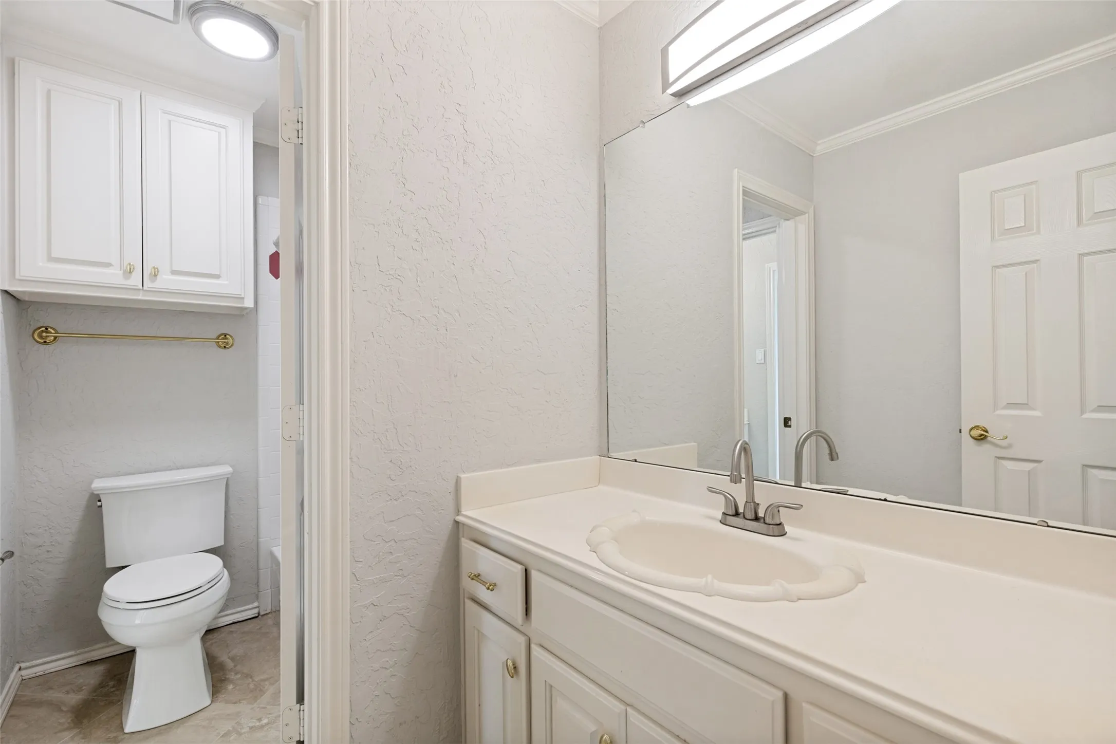 Bathroom vanity featuring a white integrated sink, polished chrome faucet, and expansive mirror
