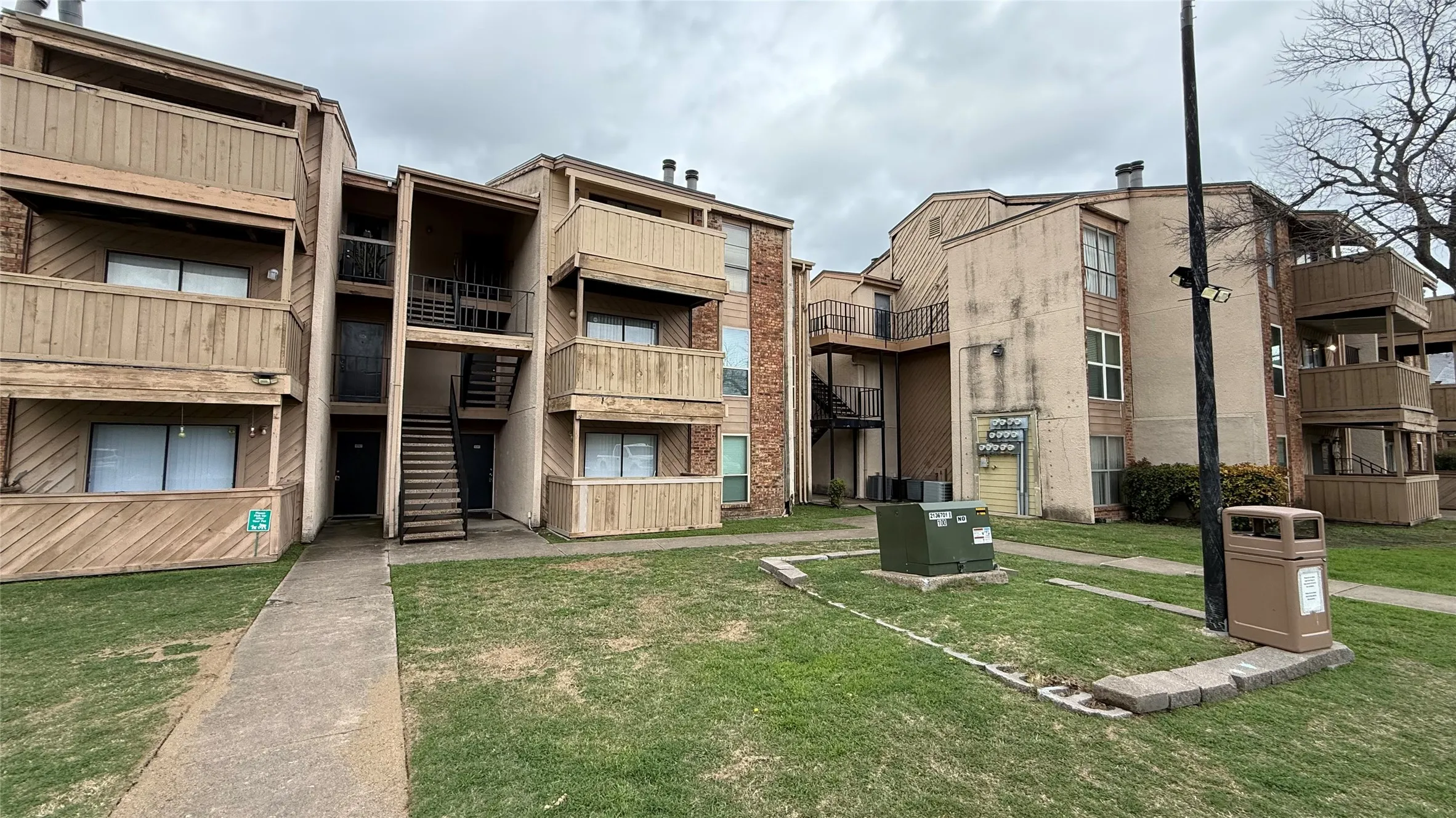 Multi-story apartment building with tan siding and wood-finish balcony railings