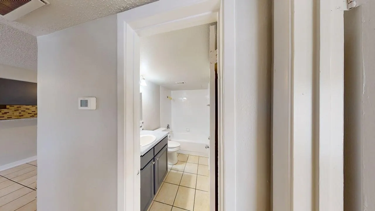 Bathroom featuring a vanity with an integrated sink, dark wood-finish cabinetry, ceramic tile flooring, and a bathtub with shower