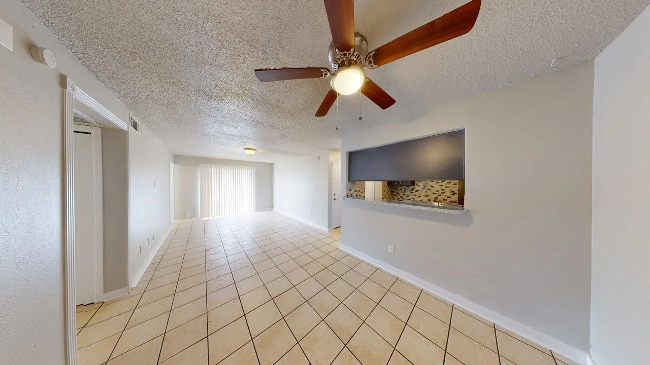 Tile flooring, ceiling fan with light fixture, sliding glass door, pass-through window, and textured walls