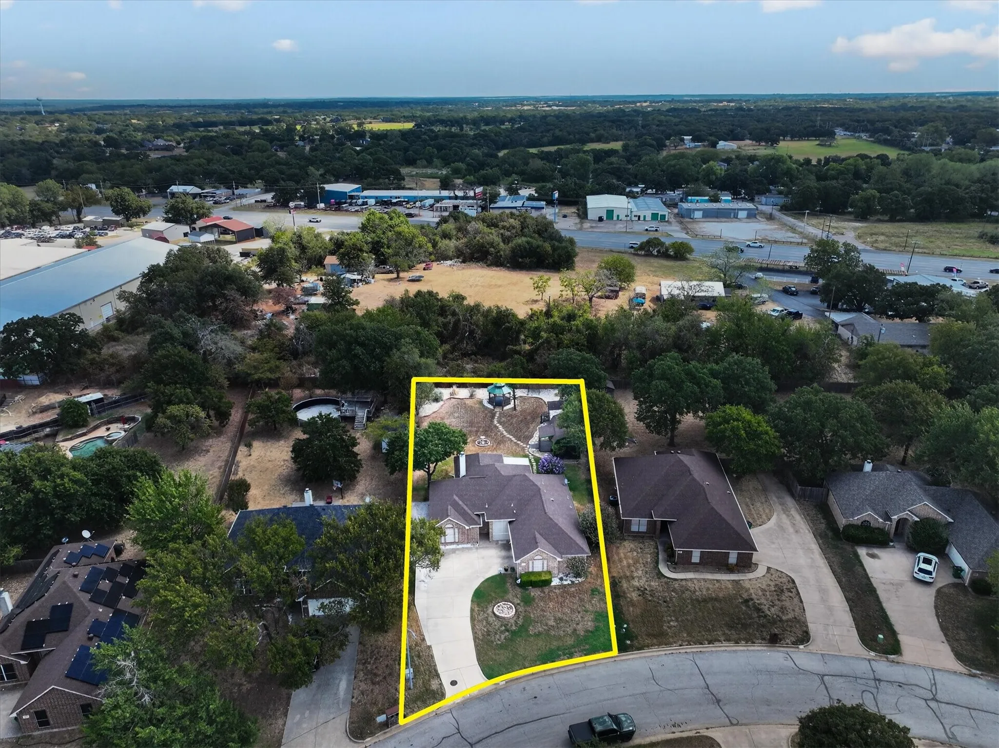 Expansive property featuring a curved concrete driveway, mature trees, and a landscaped front yard
