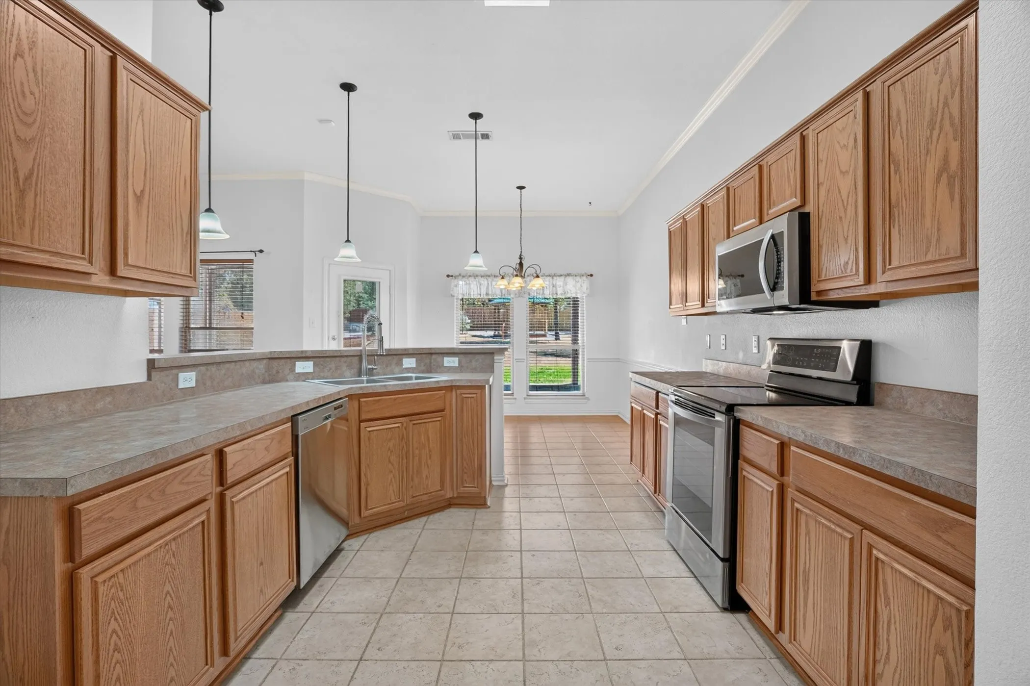 Kitchen featuring wood cabinetry, stainless steel appliances, tile flooring, and pendant lighting