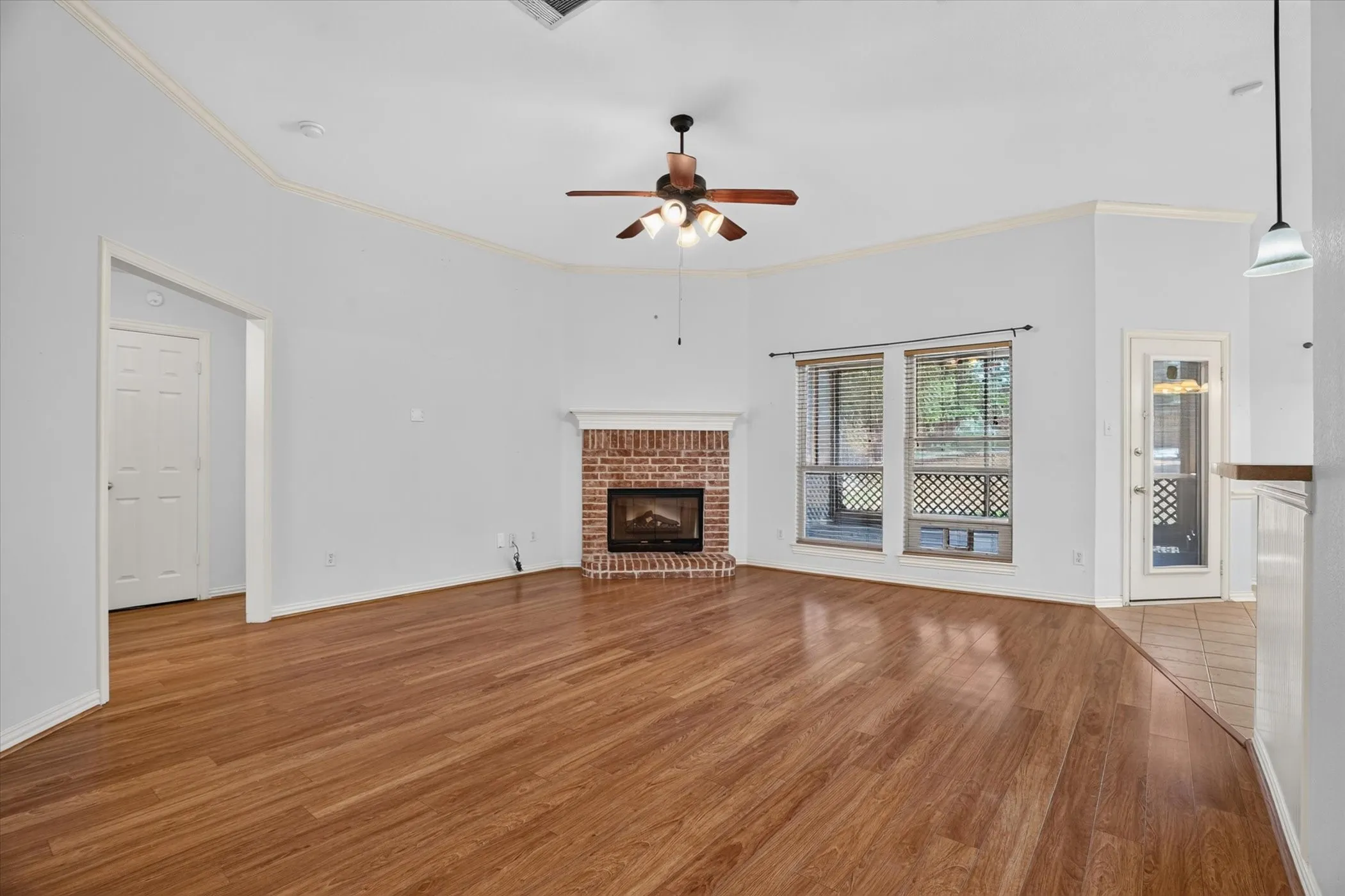 Wood-finish flooring throughout, featuring a corner brick-surround fireplace