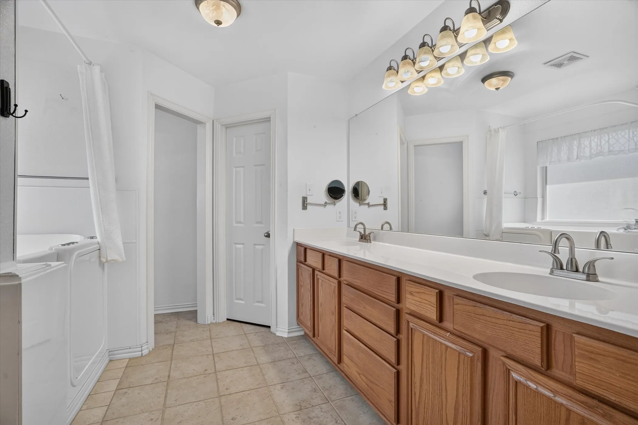 Expansive dual vanity with wood-finish cabinetry, integrated sinks, and a large wall-mounted mirror