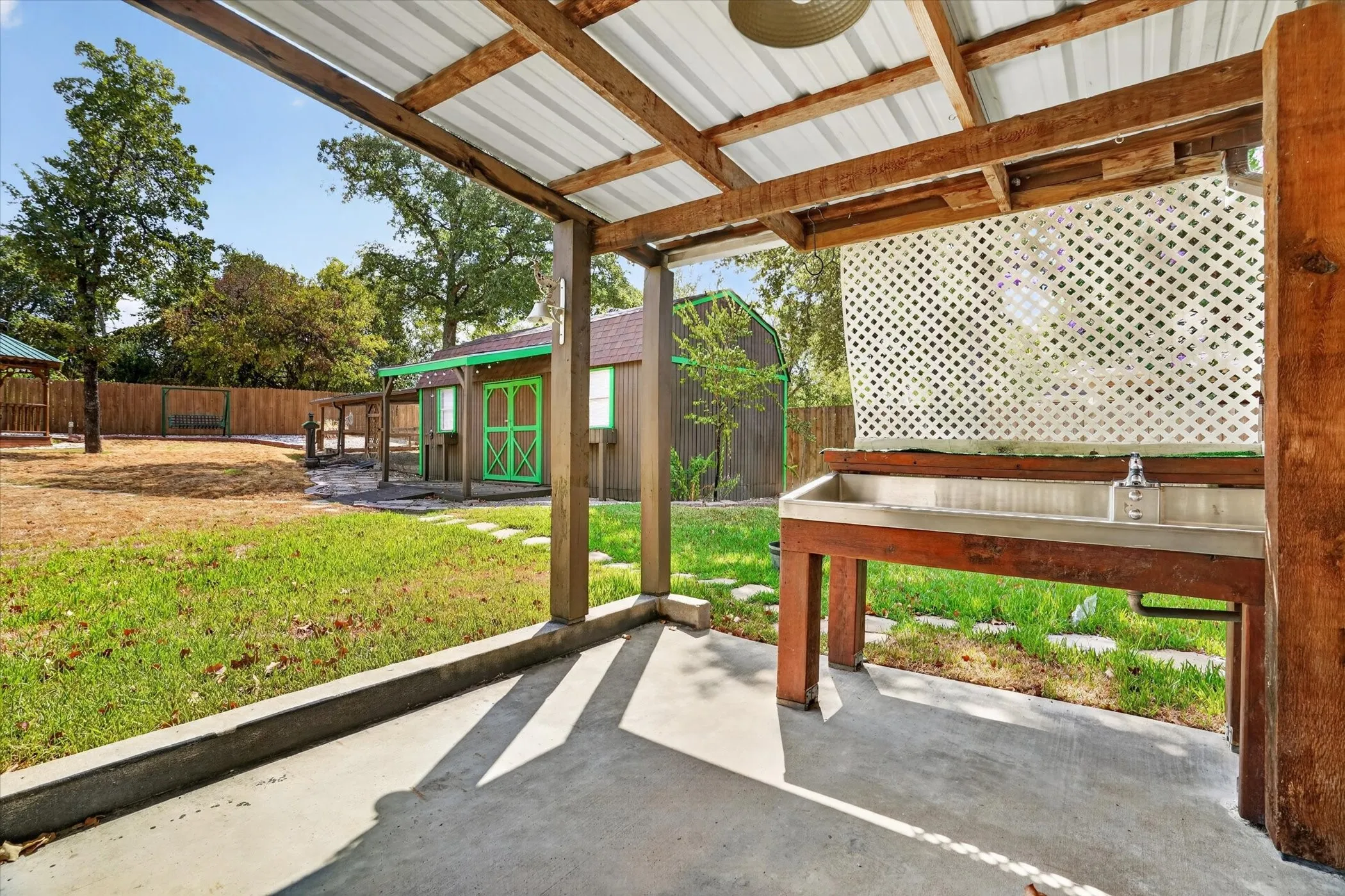 Covered patio with concrete flooring, wood frame, and corrugated metal roof