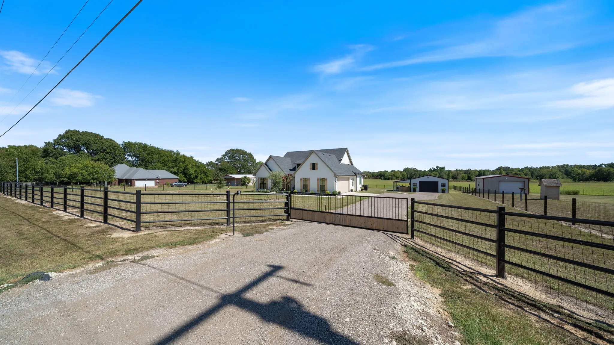 Gated entry to a residence with a light-colored exterior and dark roof