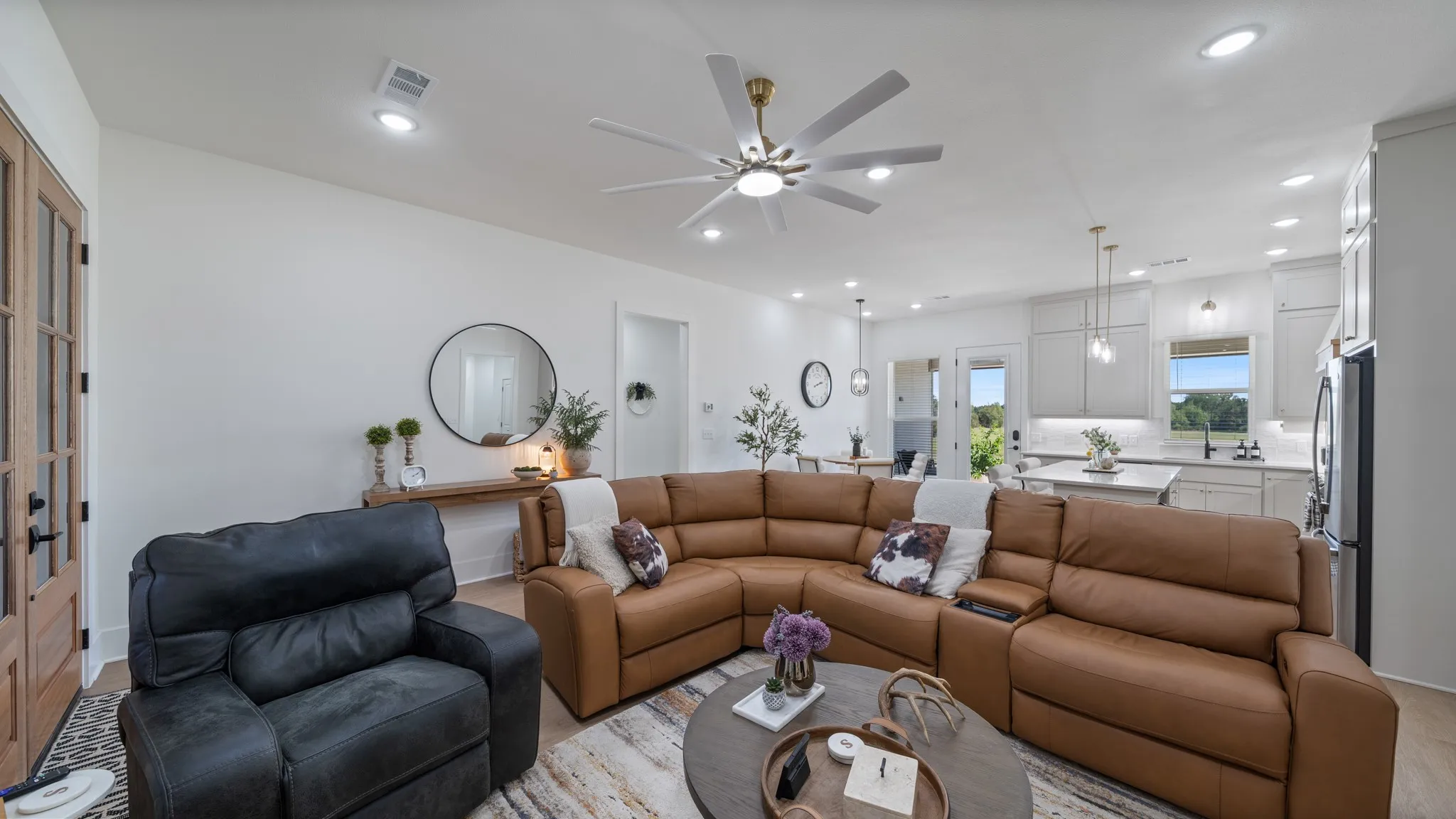 Open-concept living area featuring wood-finish flooring, a contemporary ceiling fan, recessed lighting, and French doors