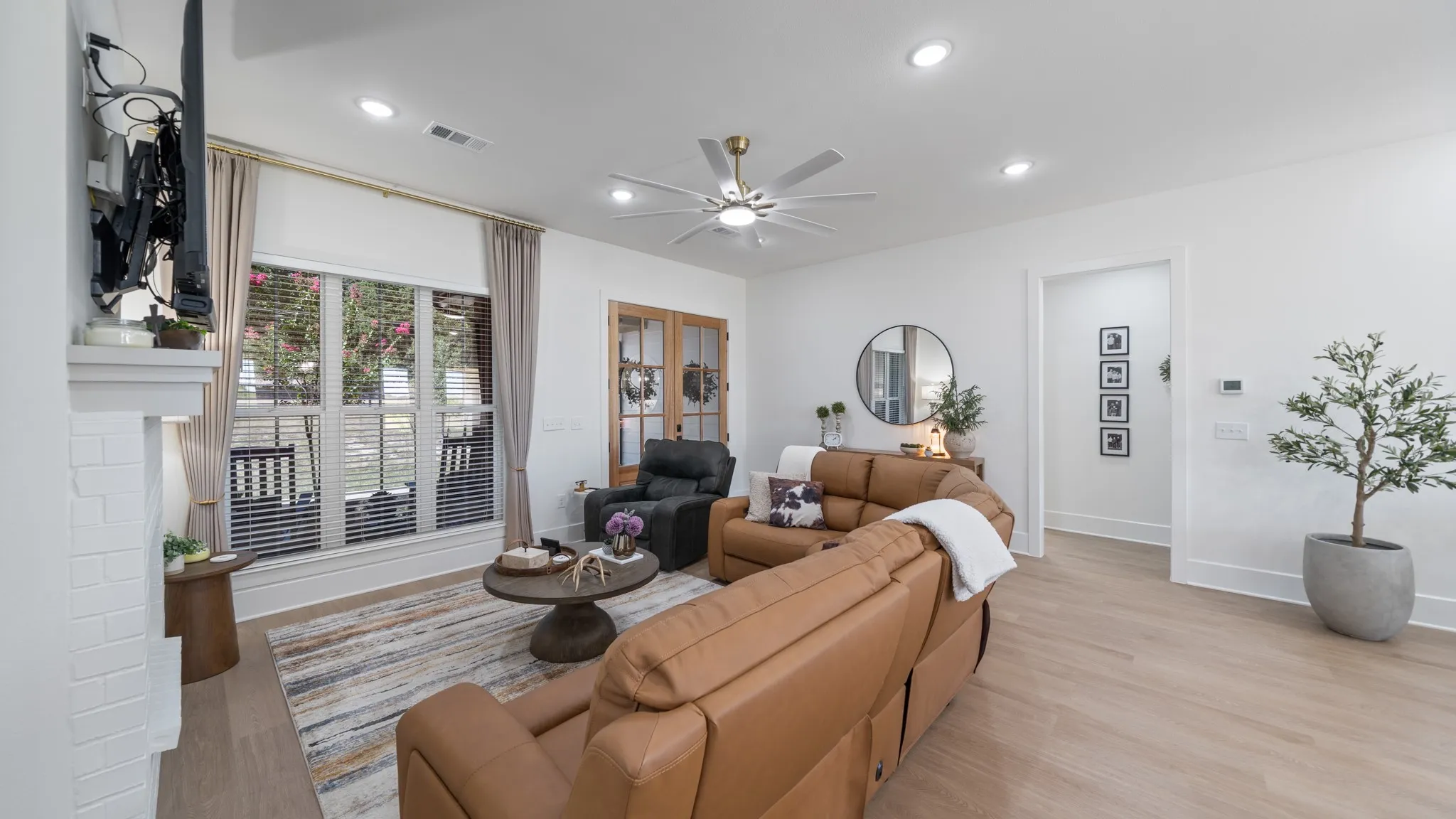 Bright open-concept living area featuring warm wood-finish flooring, recessed ceiling lighting, and a ceiling fan