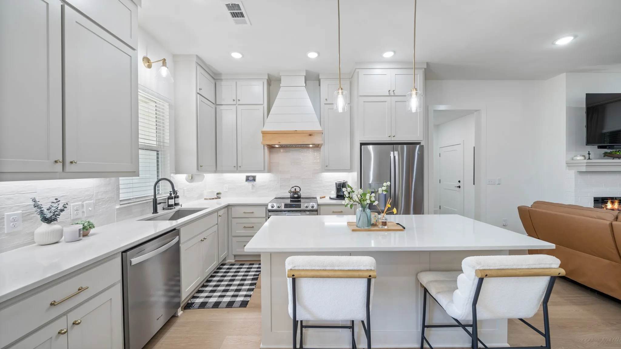 Contemporary kitchen featuring light-toned cabinetry, stainless steel appliances, a large center island with counter seating, and a decorative range hood