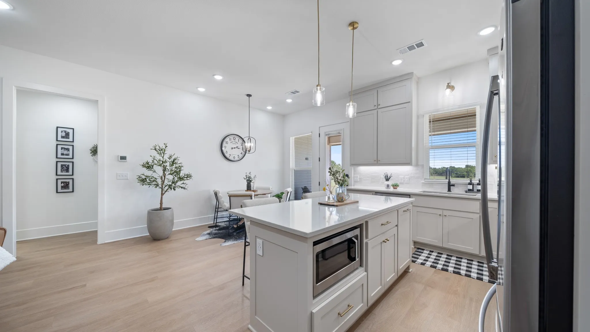 Modern kitchen featuring an island with built-in microwave, white cabinetry, integrated stainless steel appliances, and wood-finish flooring