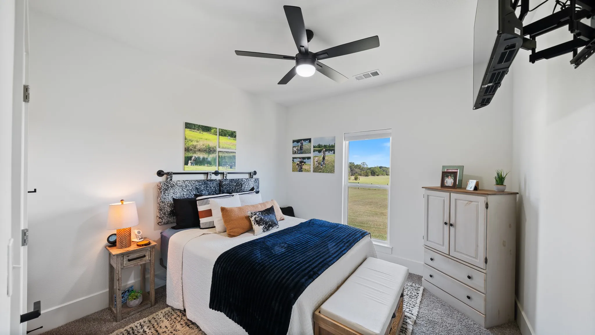 White walls with a ceiling fan, a window with a natural landscape, and carpeted flooring