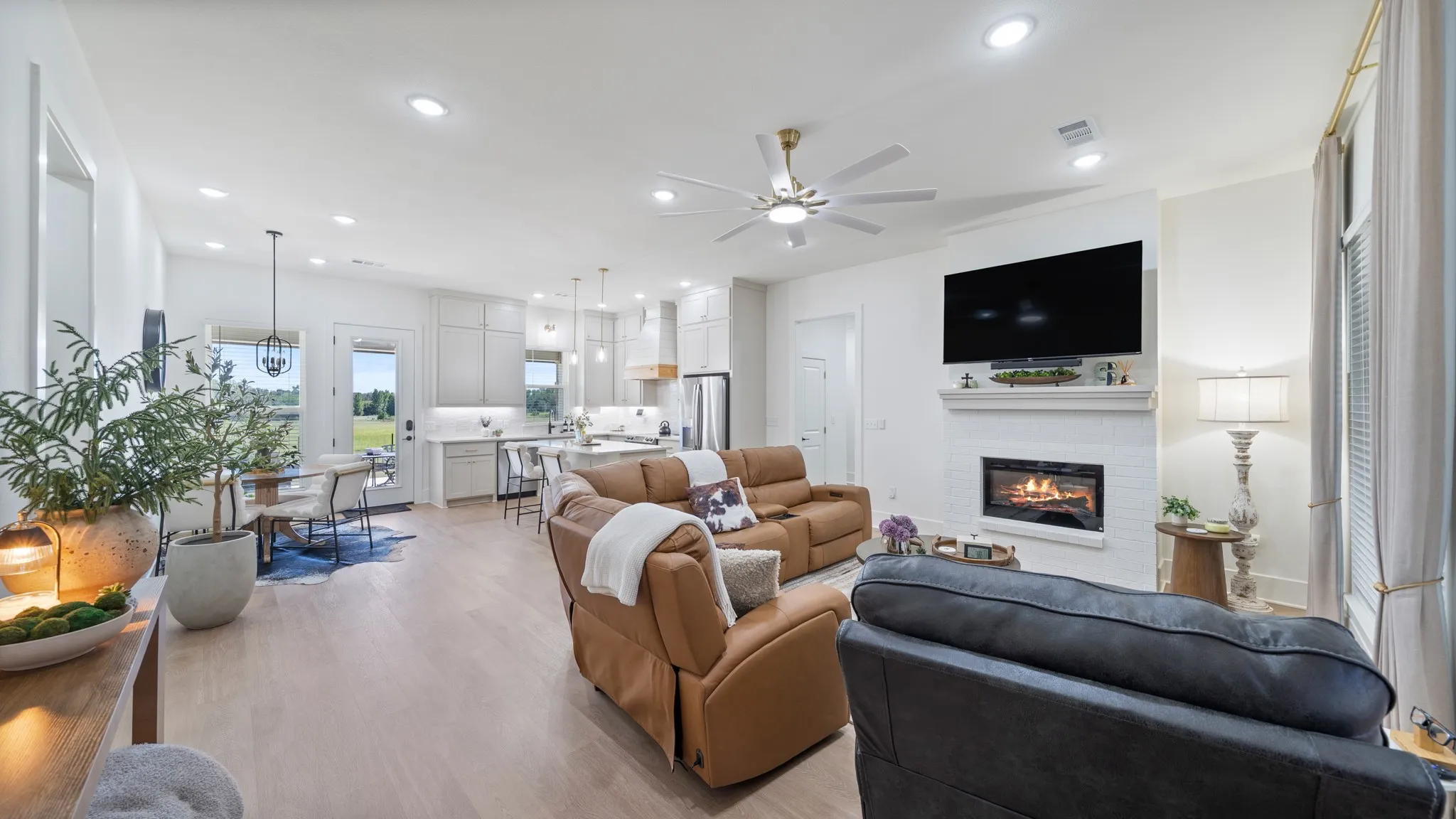 Open-concept living space featuring wood-finish flooring, recessed lighting, and a white brick fireplace