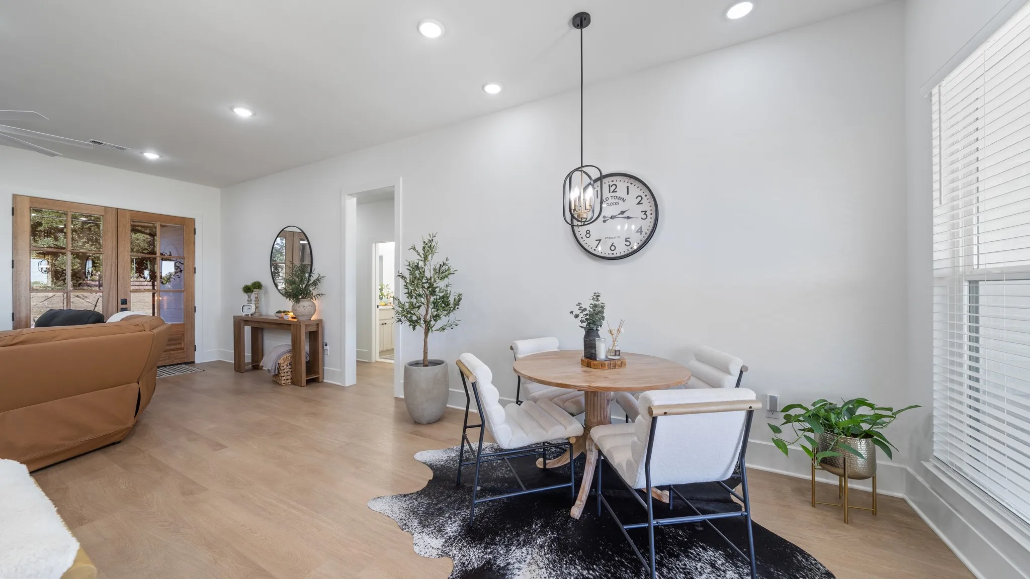 Open-concept living space featuring warm wood-finish flooring, recessed ceiling lighting, and a dining area with natural light from large windows