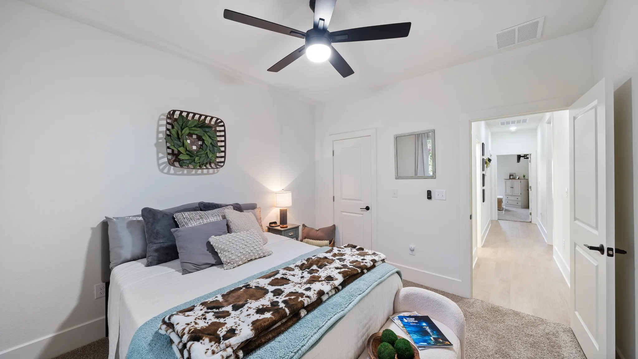 White walls with crown molding, dark ceiling fan, light wood-finish flooring, white doors with dark hardware