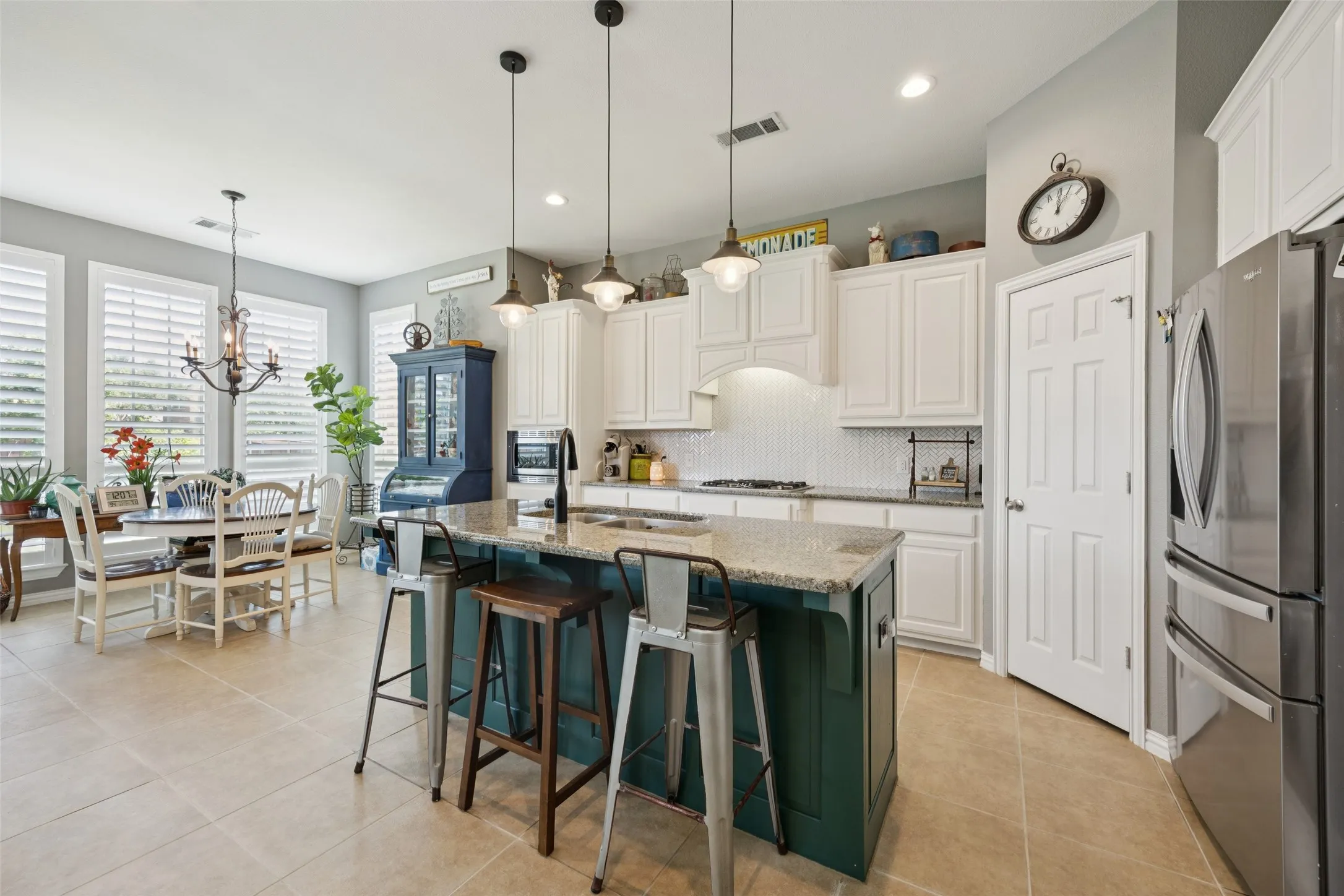 Kitchen with an island featuring a granite countertop, white cabinetry, and a tile backsplash