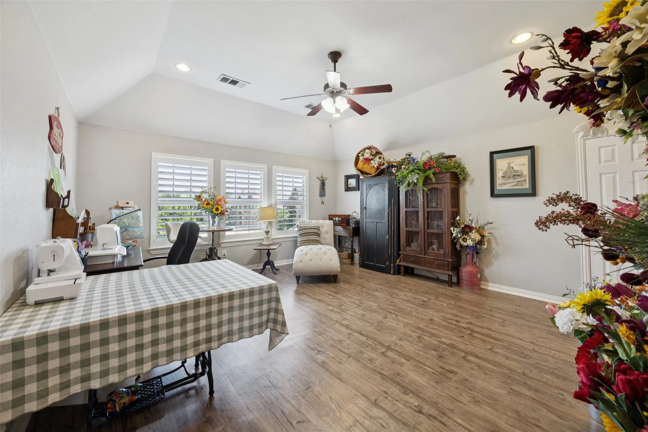 Wood-finish flooring, vaulted ceiling, recessed lighting, ceiling fan, and multiple windows with plantation shutters