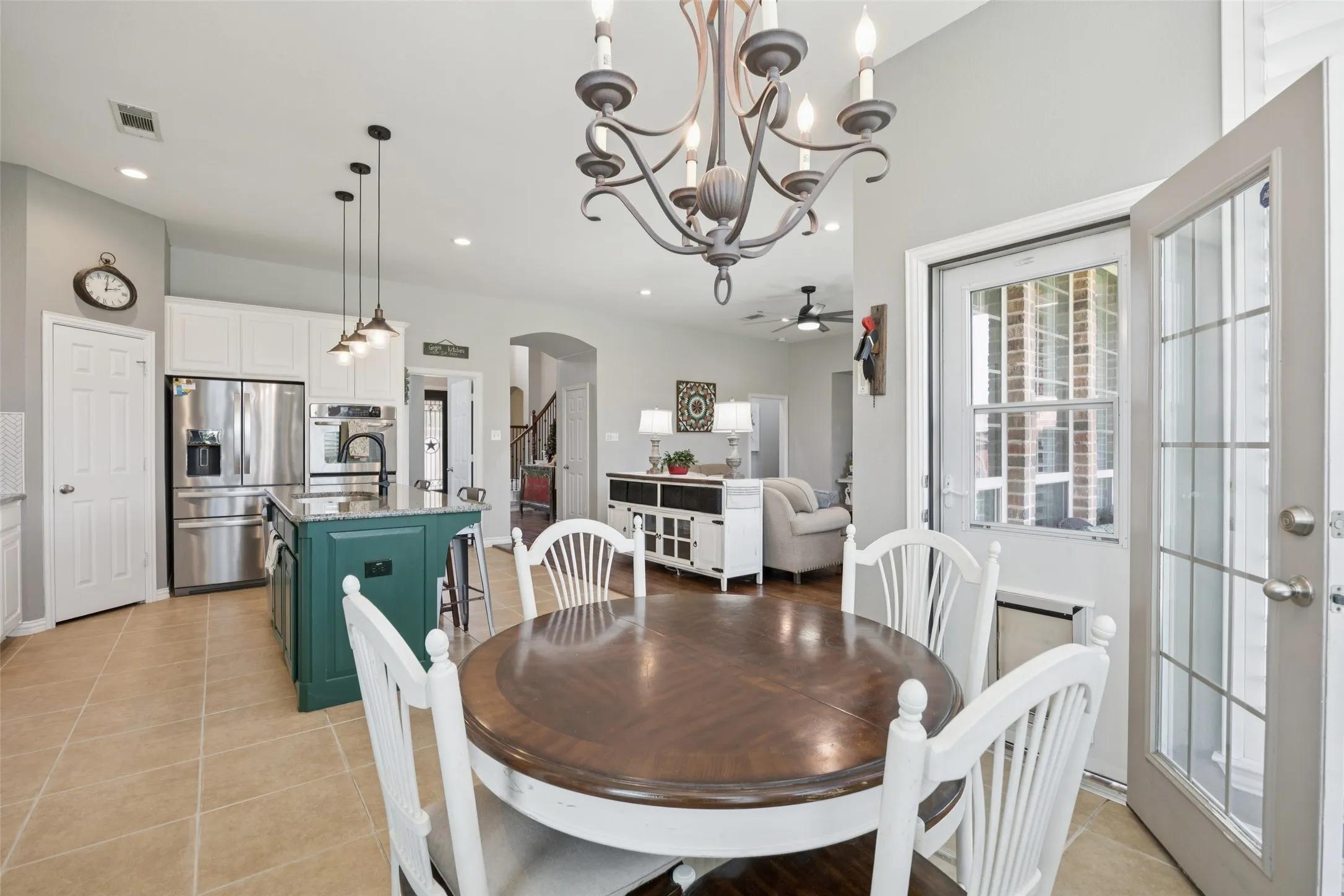 Kitchen featuring an island with a dark green base, stainless steel appliances, and white cabinetry