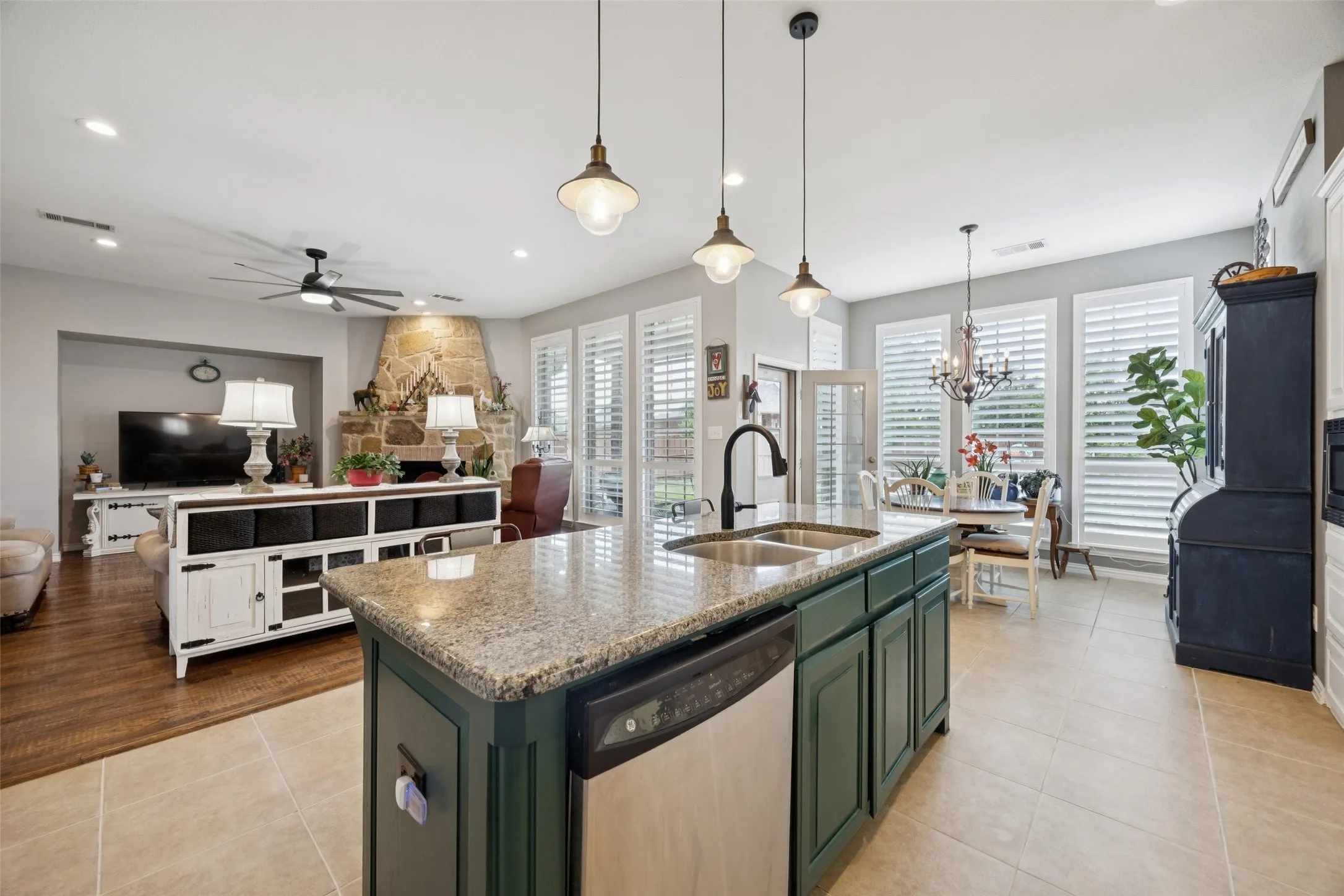 Kitchen island with a granite countertop, dual basin sink, and pendant lighting