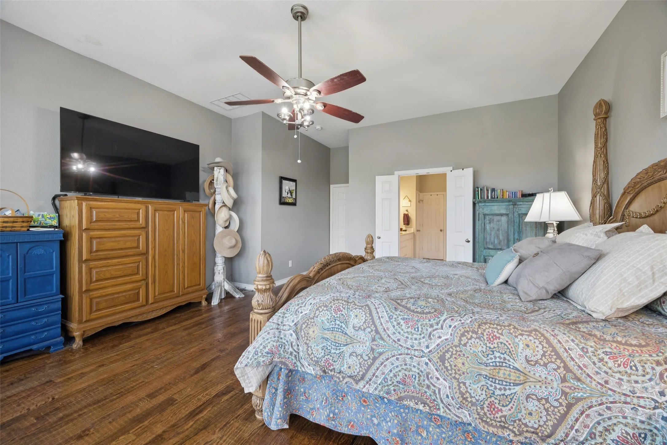 Wood-finish flooring, ceiling fan with integrated lighting, and a double-door entry to an additional space
