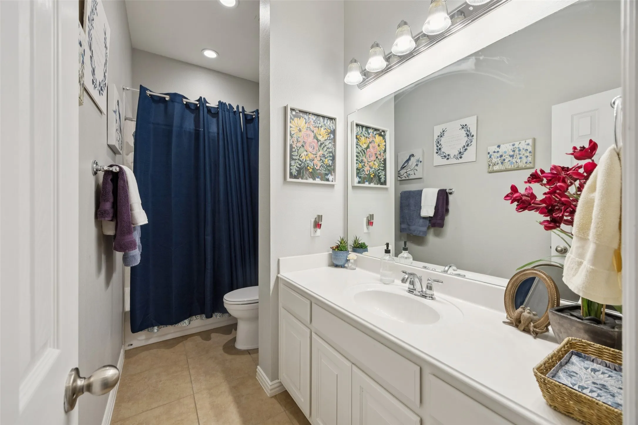 Vanity with integrated sink and chrome faucet, large vanity mirror, recessed ceiling lighting, tile flooring, and a white toilet