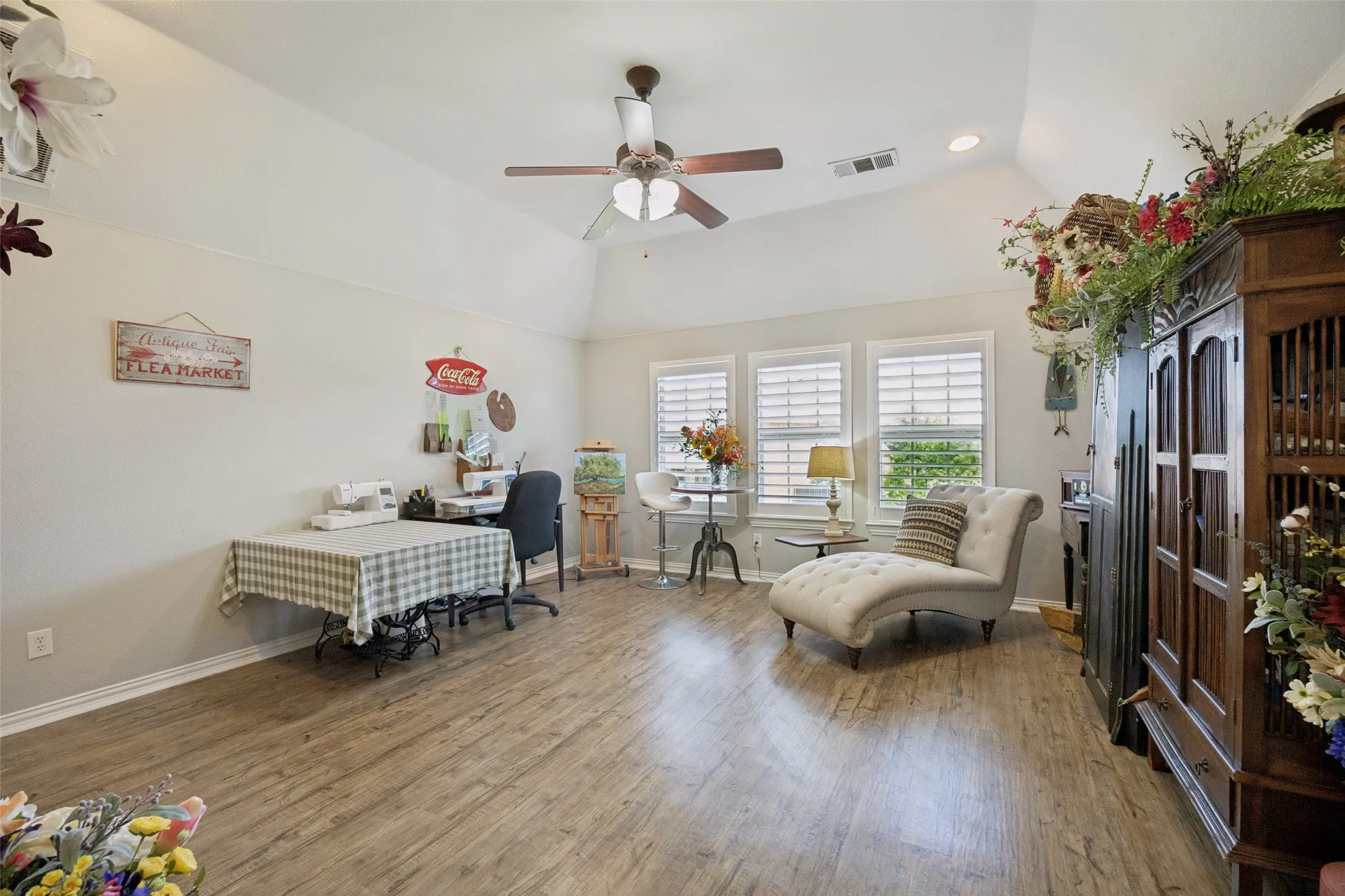 Vaulted ceiling with a ceiling fan, wood-finish flooring, recessed lighting, and three windows with plantation shutters