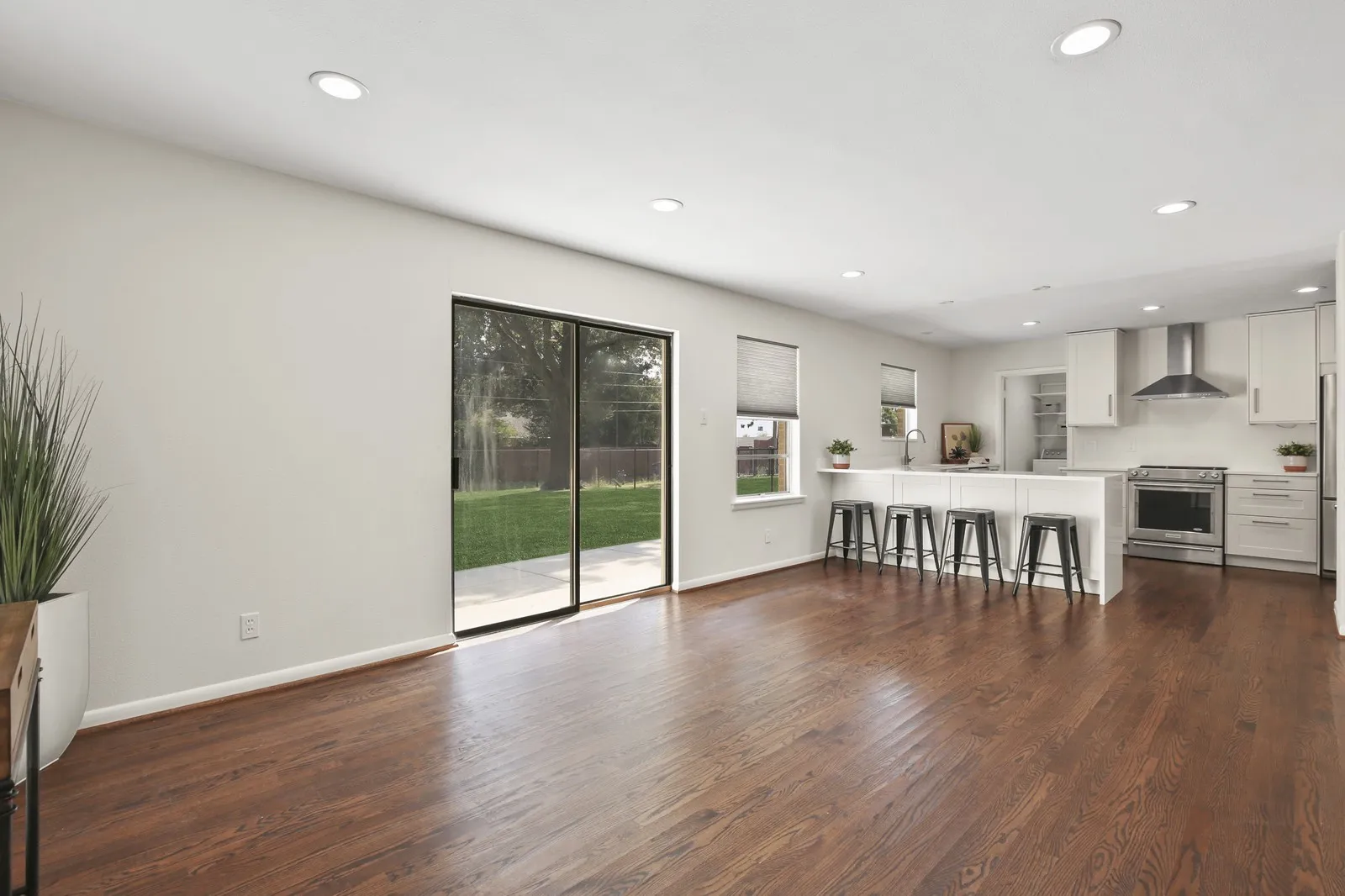 Open-concept living space with dark wood-finish flooring, recessed lighting, and sliding glass doors leading to a private outdoor area