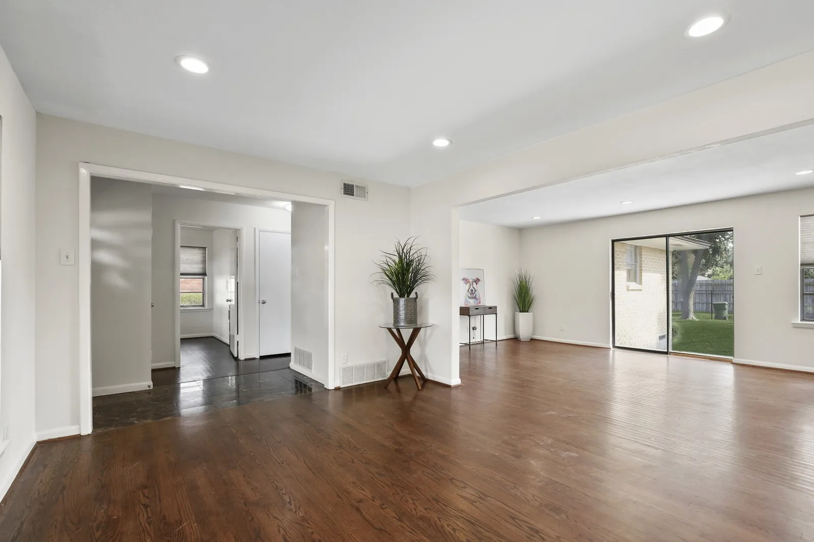 Recessed lighting, dark wood-finish flooring, sliding glass door, white walls, and bright white trim
