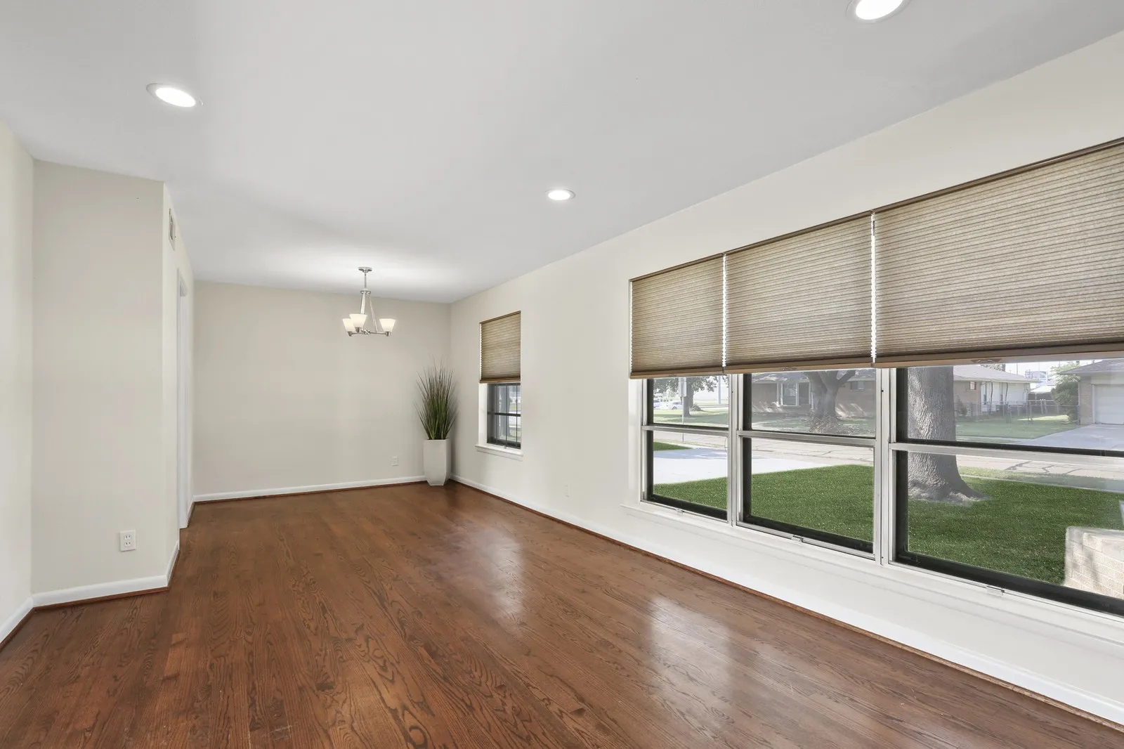 Hardwood flooring, recessed ceiling lighting, a contemporary chandelier, multiple windows, and neutral wall tones
