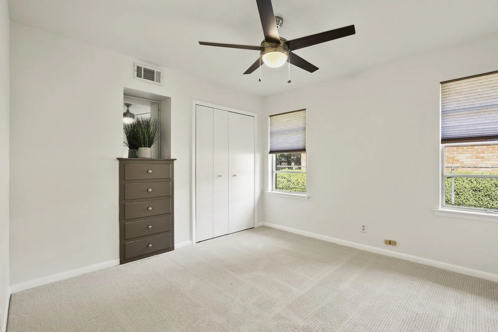 Plush carpet flooring, ceiling fan with integrated lighting, built-in dresser, bi-fold closet doors, and multiple windows with blinds