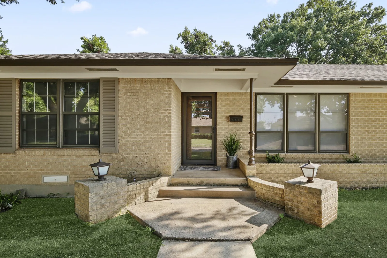 Brick exterior featuring brown shutters and an asphalt shingle roof