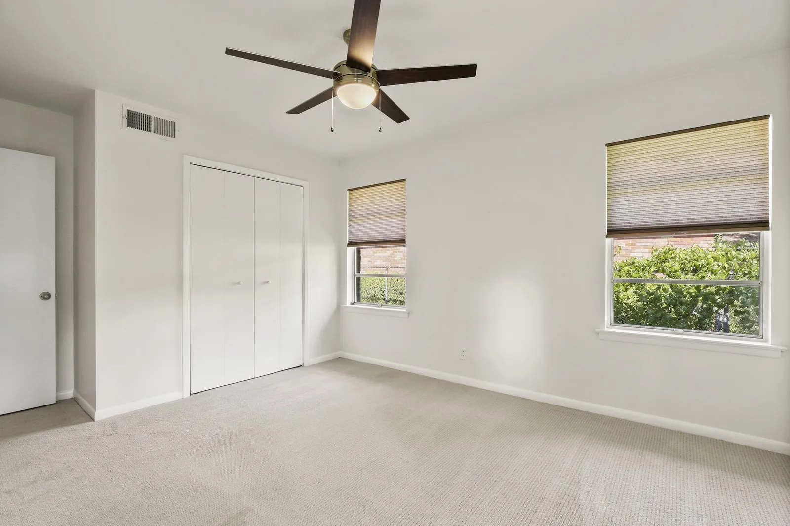 Recessed lighting, wood-finish ceiling fan, two windows with blinds, and built-in closet with bifold doors