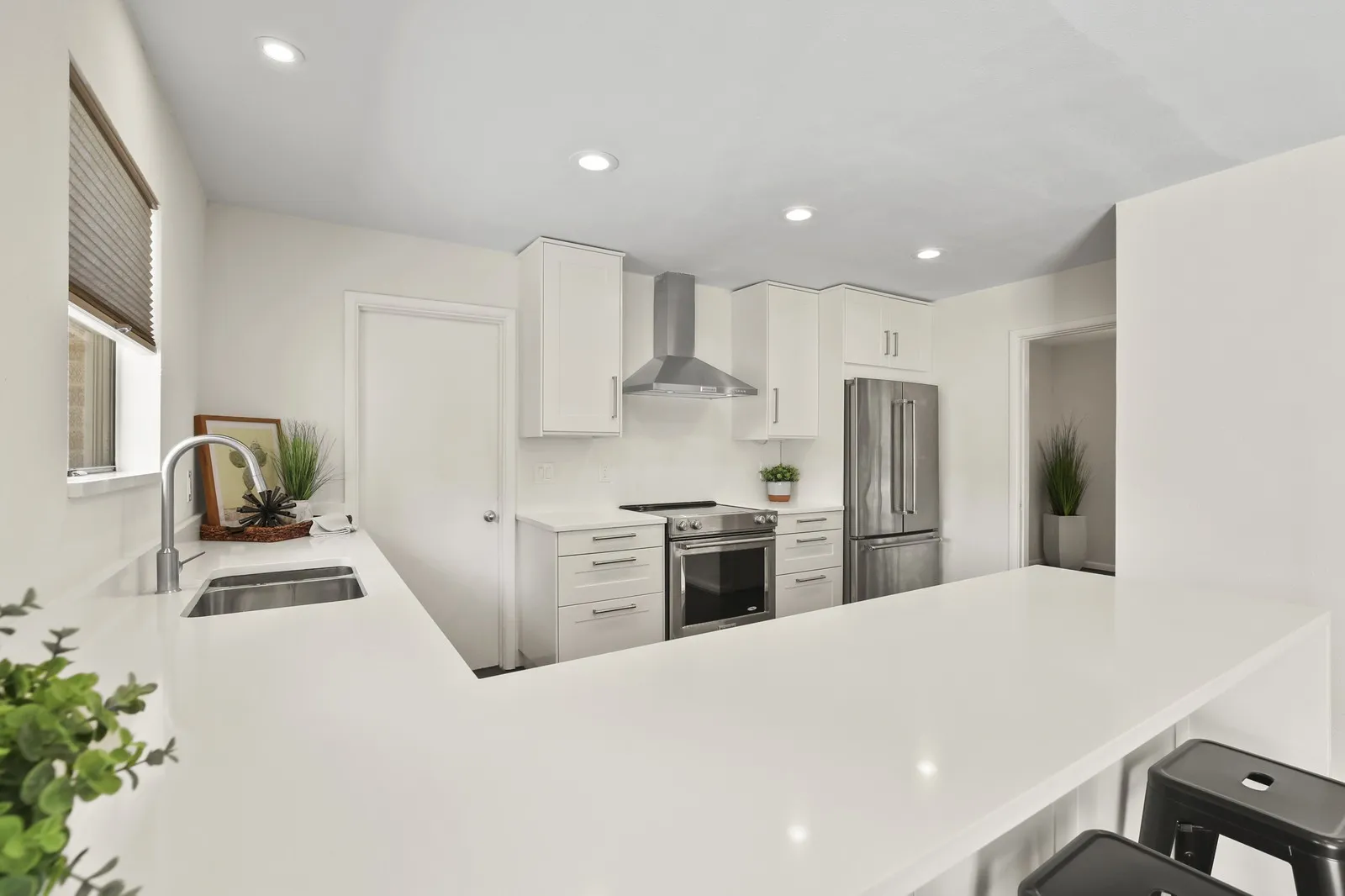 Kitchen featuring white cabinetry, stainless steel appliances, recessed lighting, and expansive countertops with an undermount sink