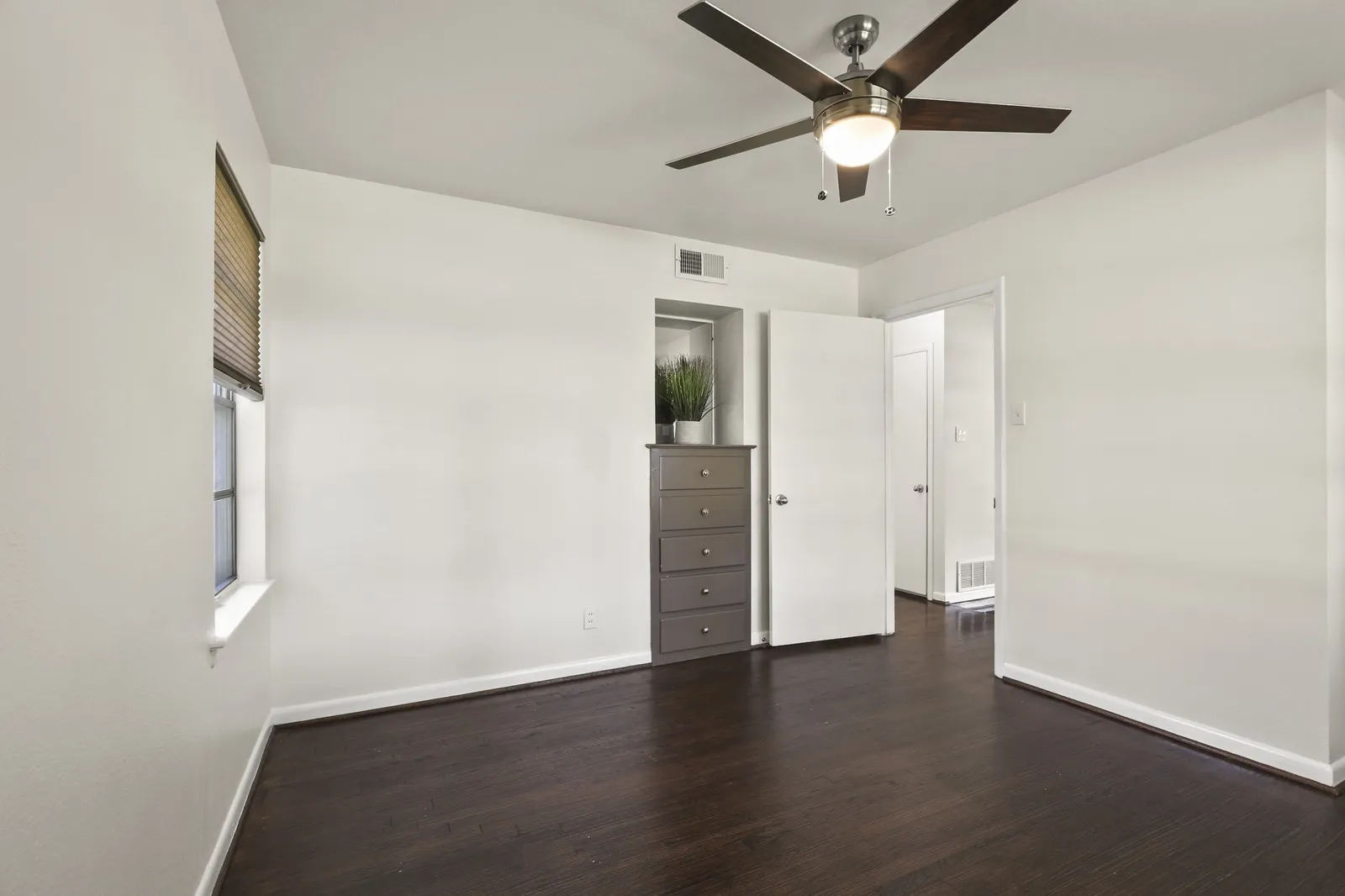 Wood-finish flooring, ceiling fan with integrated lighting, white walls, and white trim