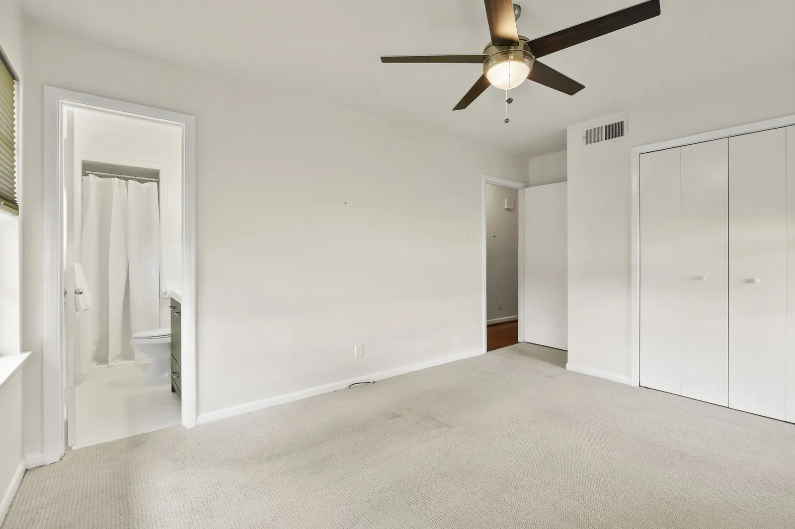 Carpeted room with a ceiling fan, window with blinds, and built-in closet with bi-fold doors