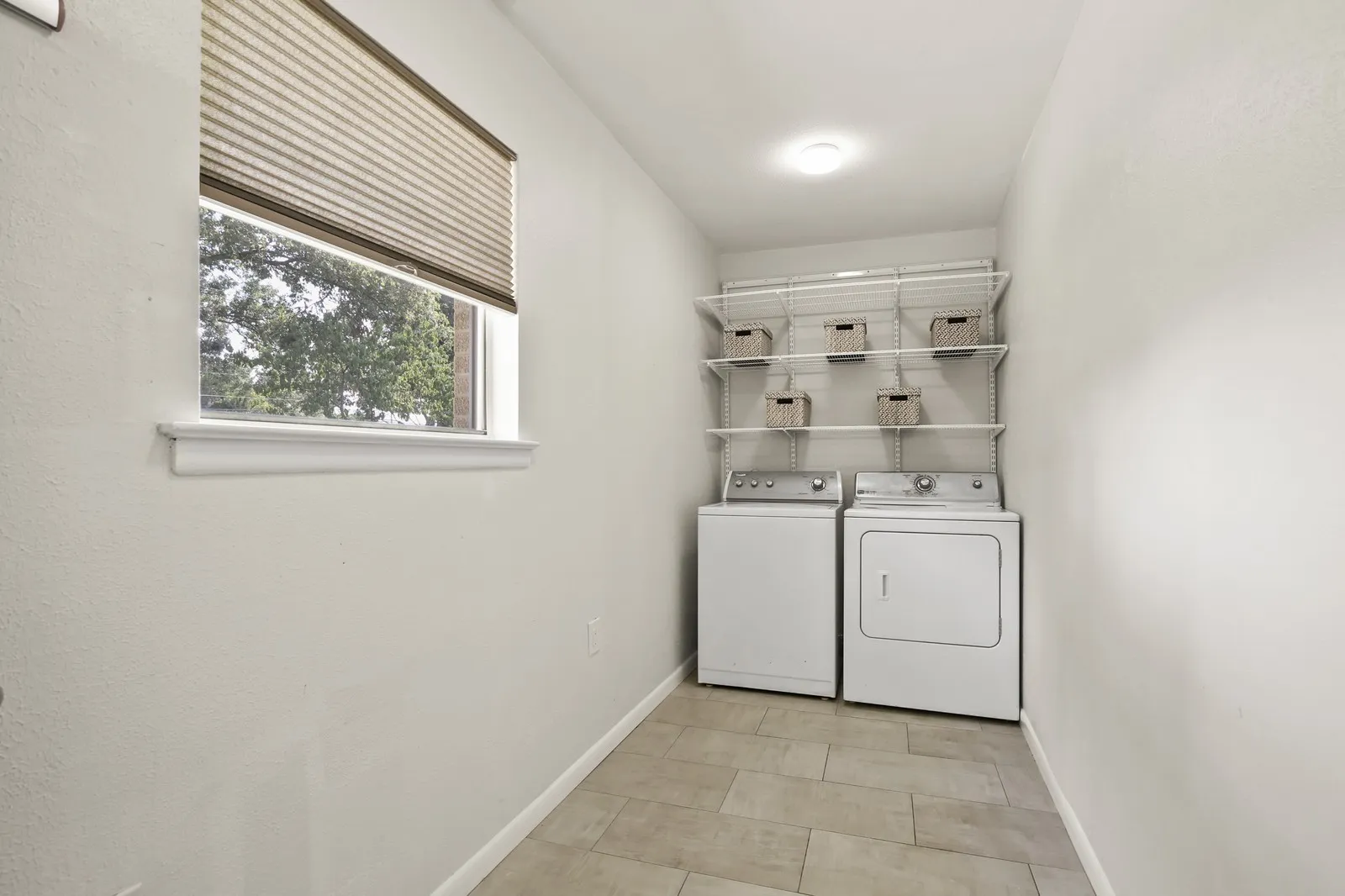 Recessed lighting, tile flooring, window with pleated shade, and built-in shelving system