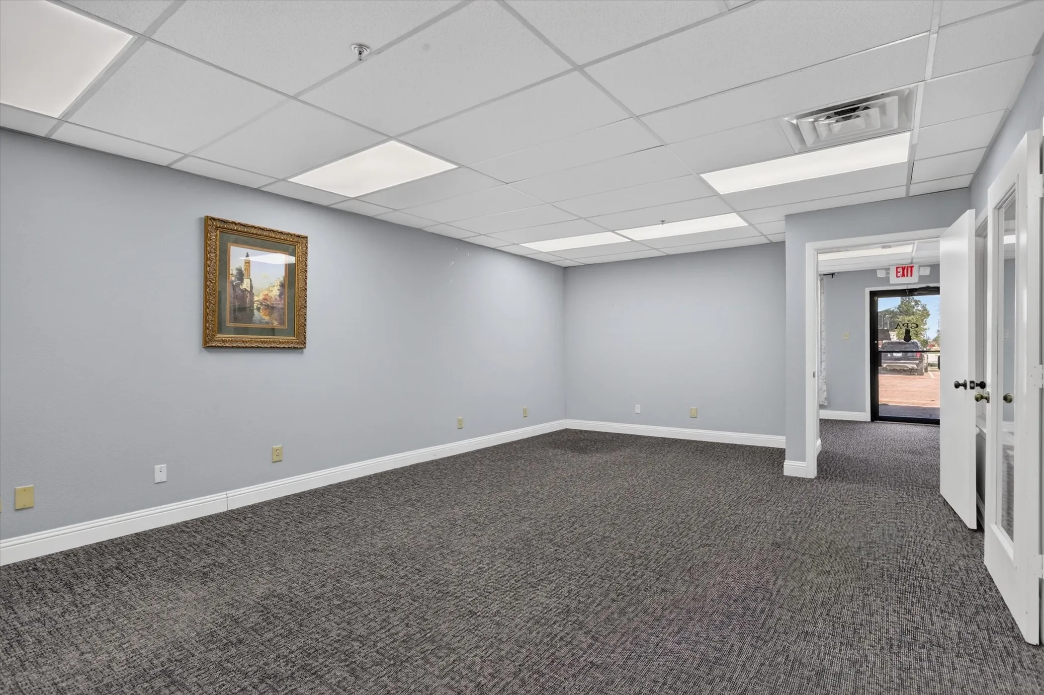 Gray carpeted flooring, light gray walls, white drop ceiling with recessed lighting, and white trim