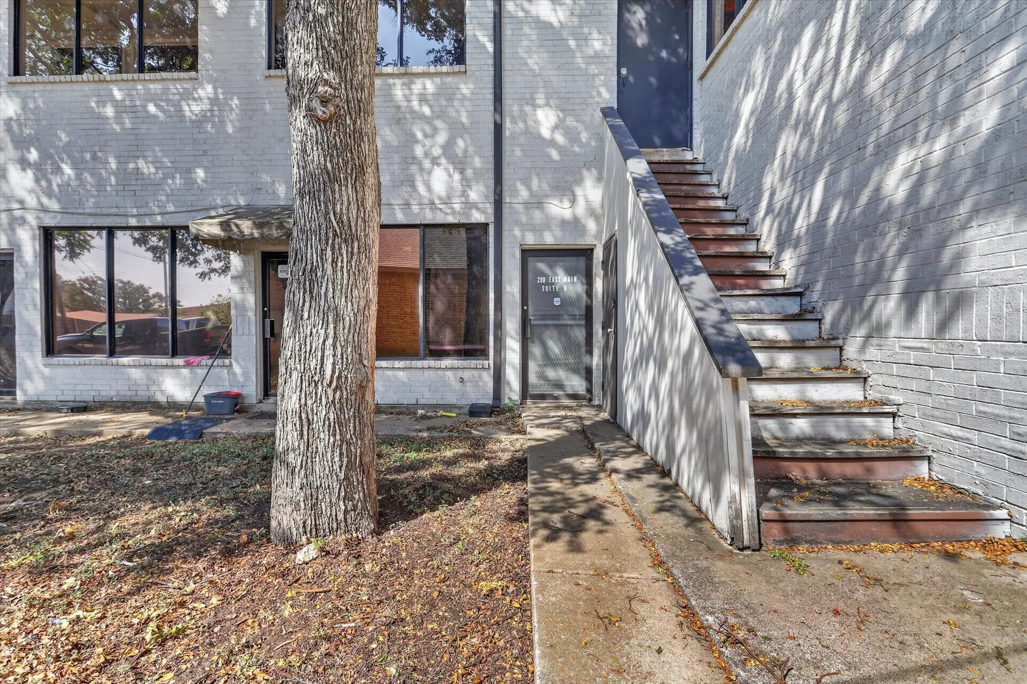 Brick exterior with multiple windows, concrete walkway, and exterior staircase
