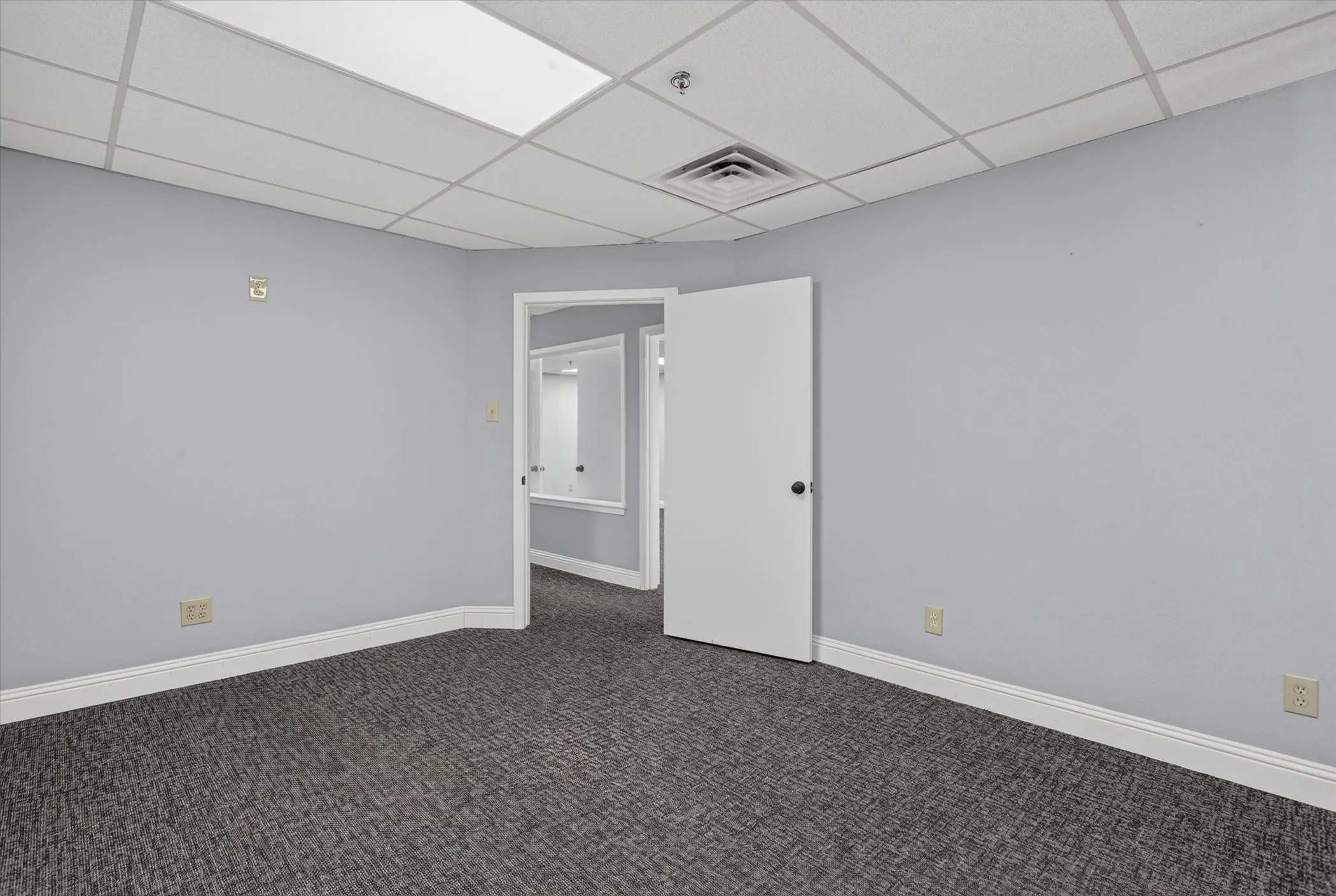 Wall-to-wall carpeting, light gray wall finish, white baseboards, white ceiling grid, and recessed lighting