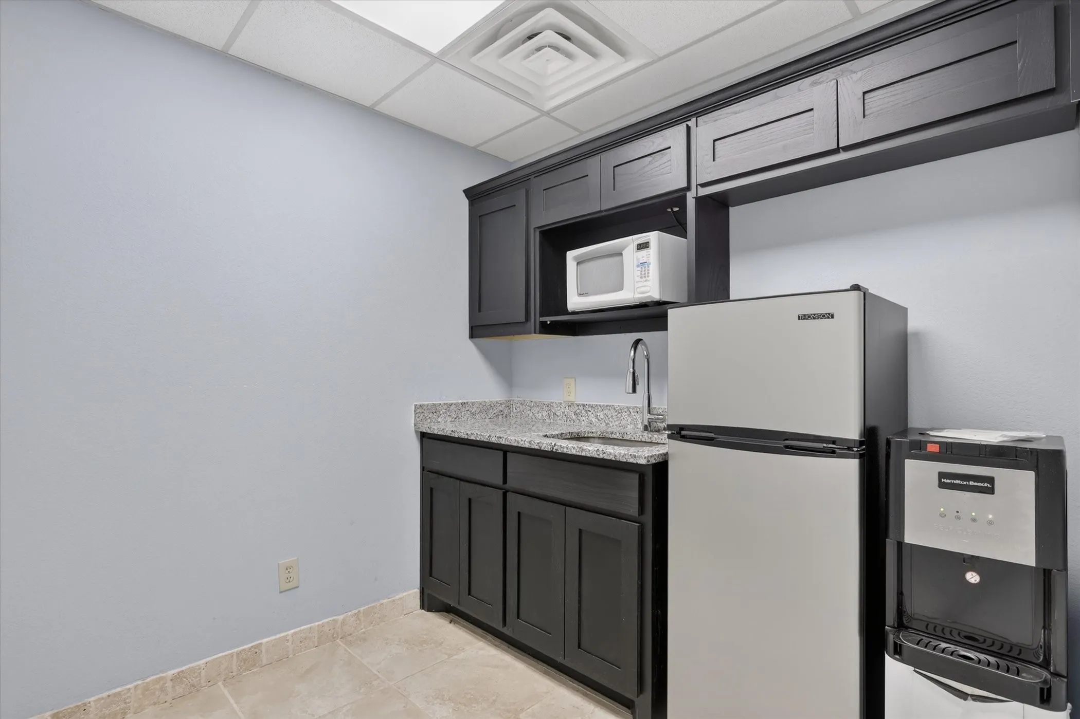 Built-in cabinetry with dark wood-finish, granite-style countertop, and a stainless steel sink with a gooseneck faucet