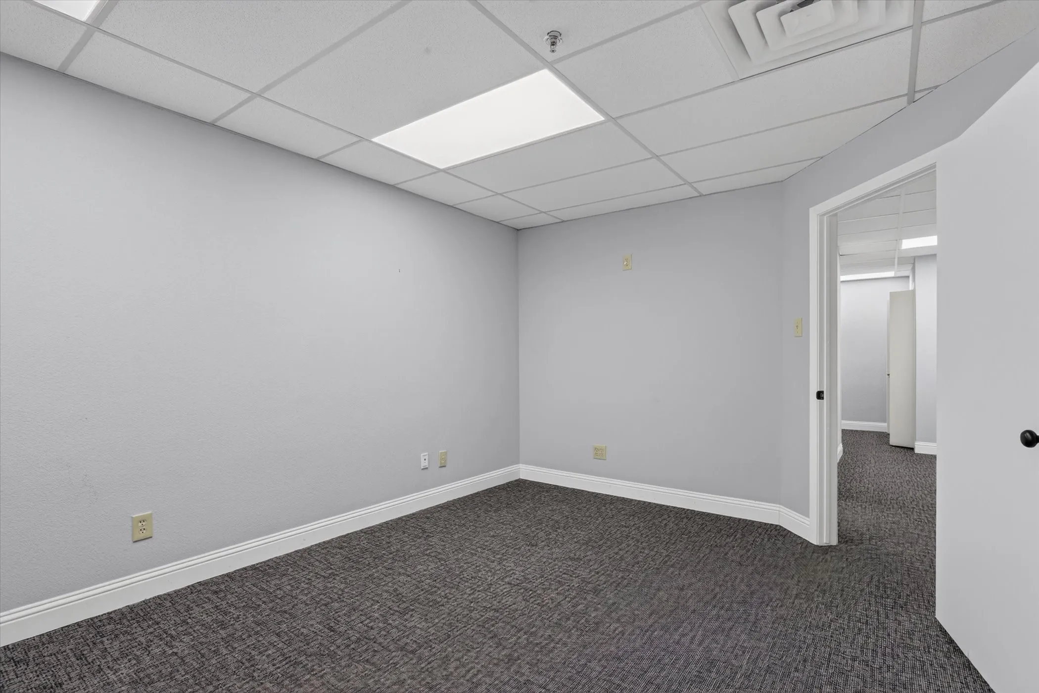 Neutral gray wall finish, drop ceiling, recessed lighting, and dark gray carpet flooring