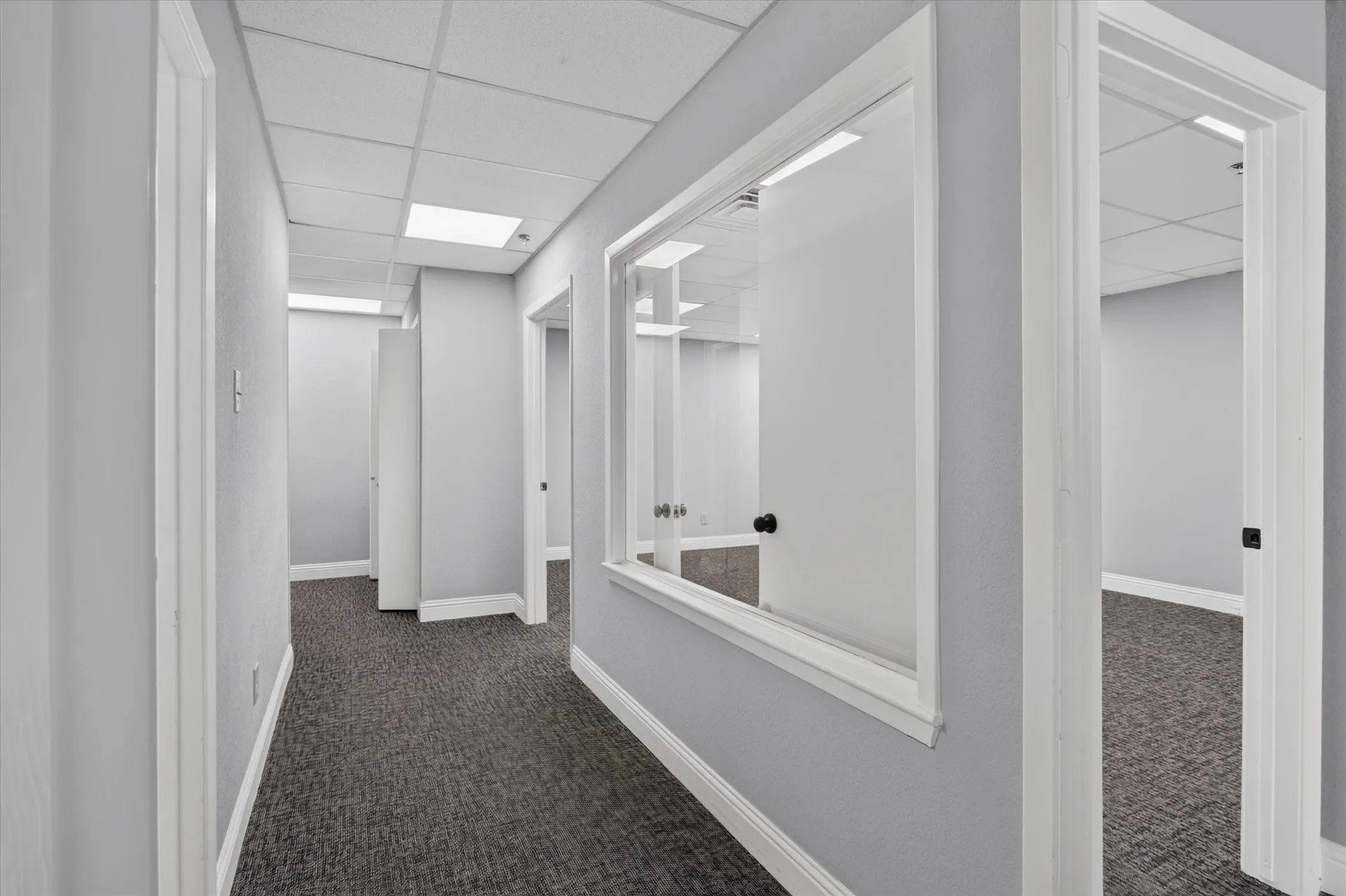 Hallway with carpet flooring, white trim, recessed lighting, and multiple entryways with doors
