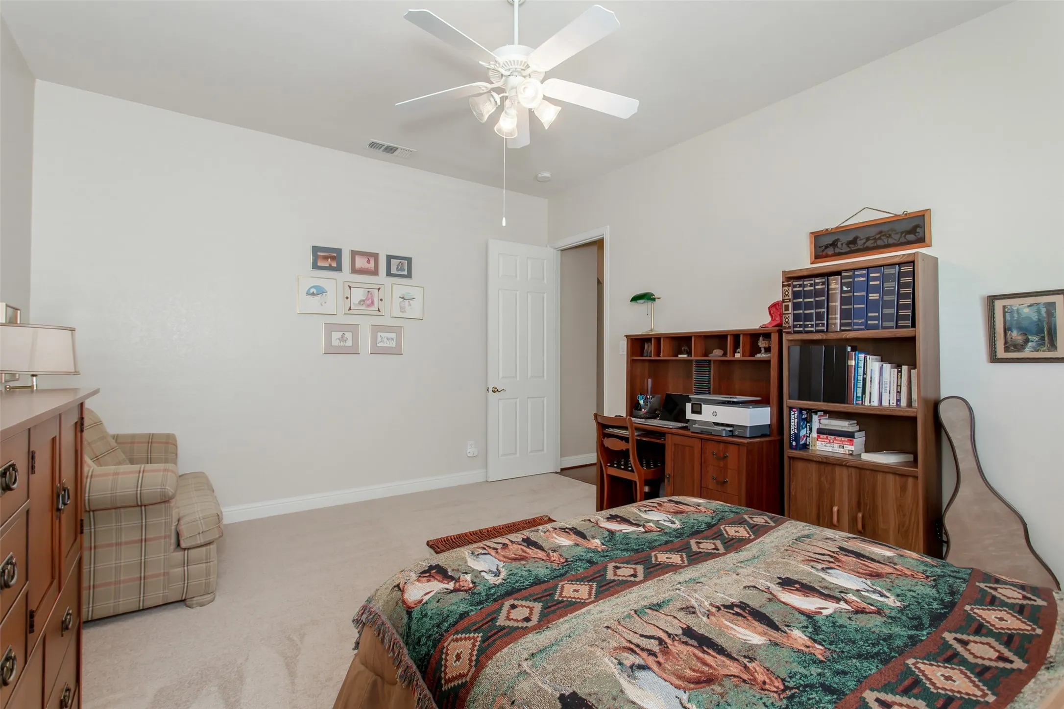 Carpeted room with a ceiling fan, white paneled door, and neutral wall paint