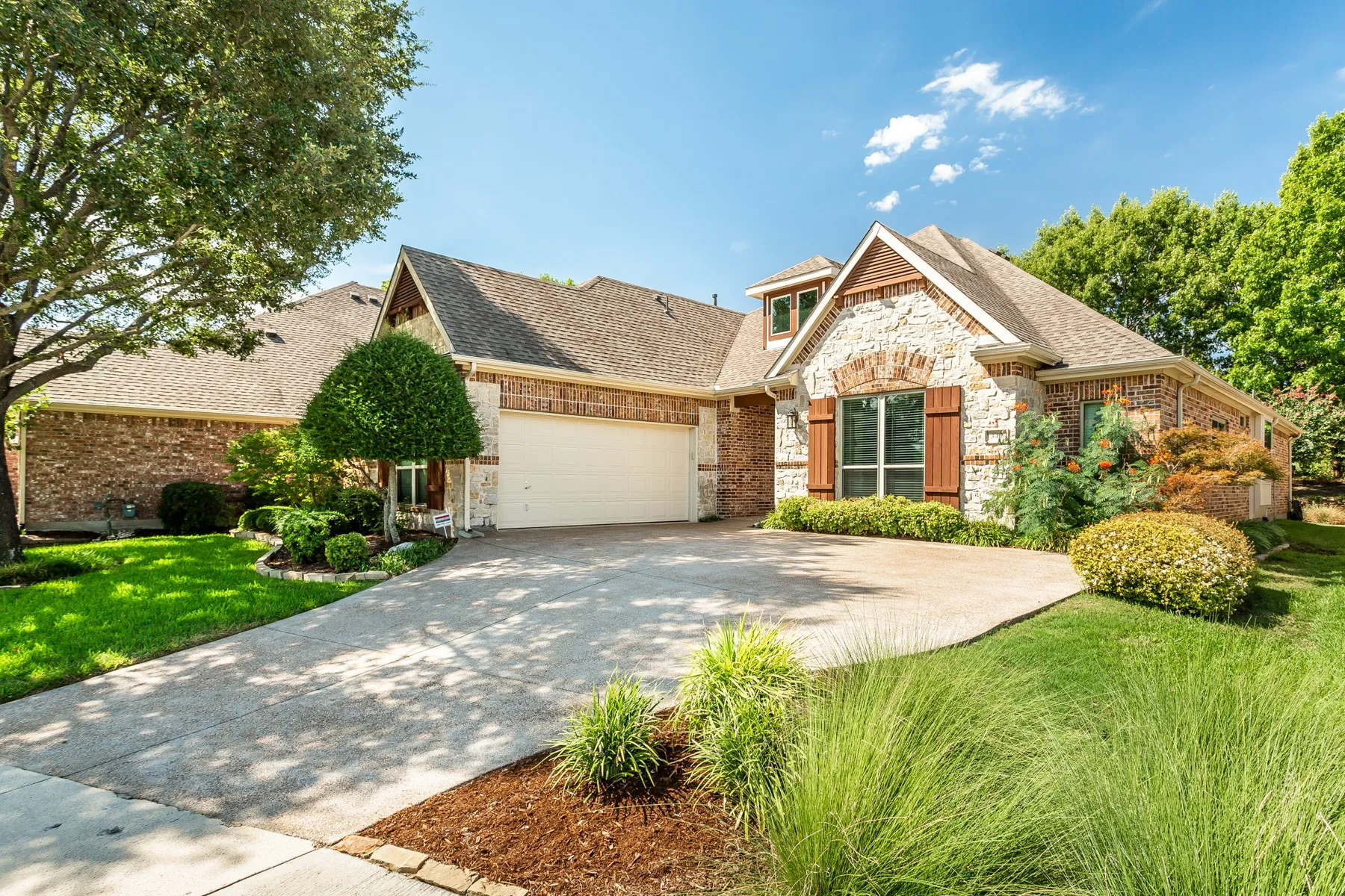 Stone and brick exterior with wood shutters, a gabled roofline, and an attached garage