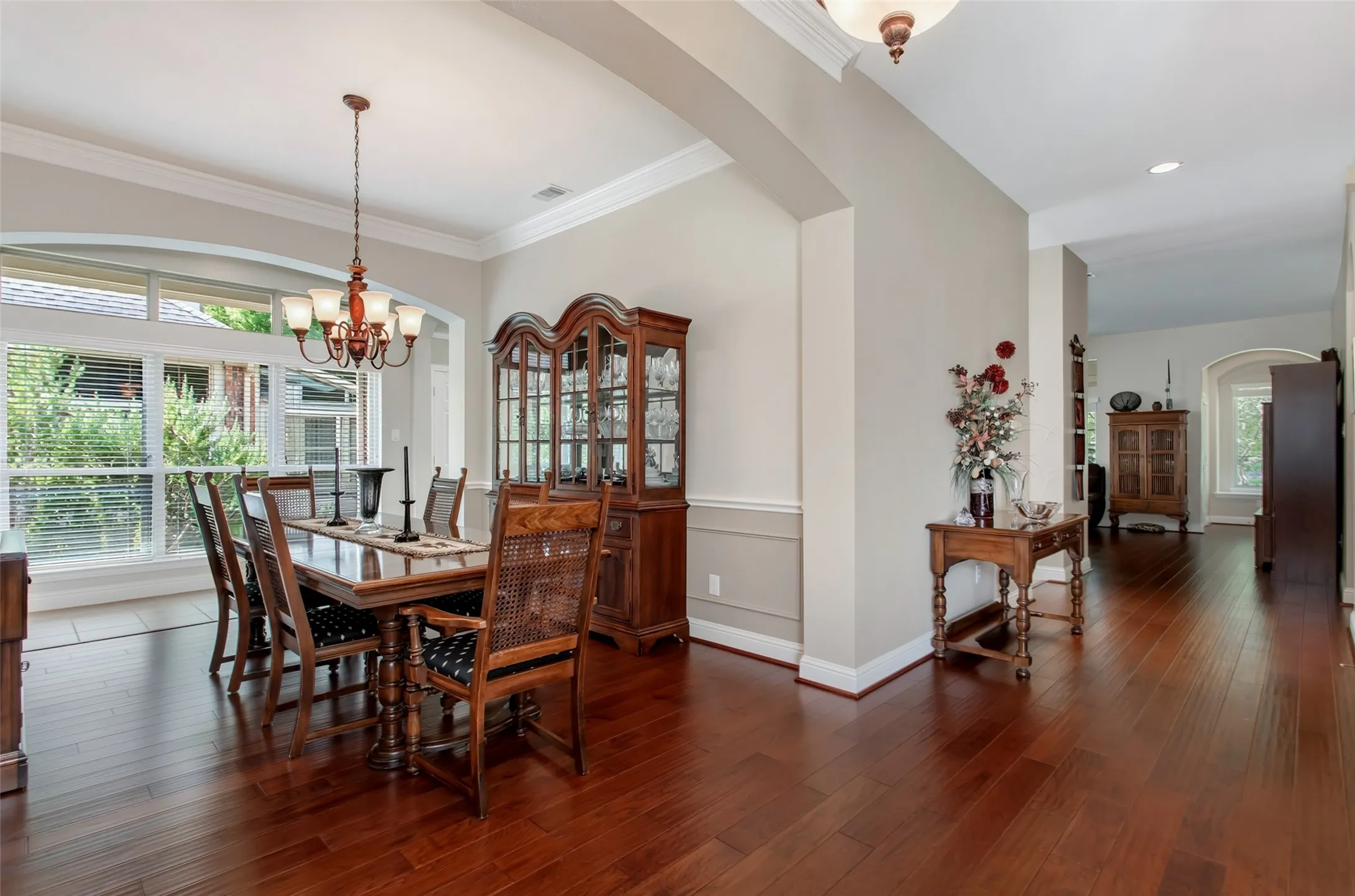 Hardwood flooring throughout, featuring crown molding, arched room openings, and a large window with transom detail