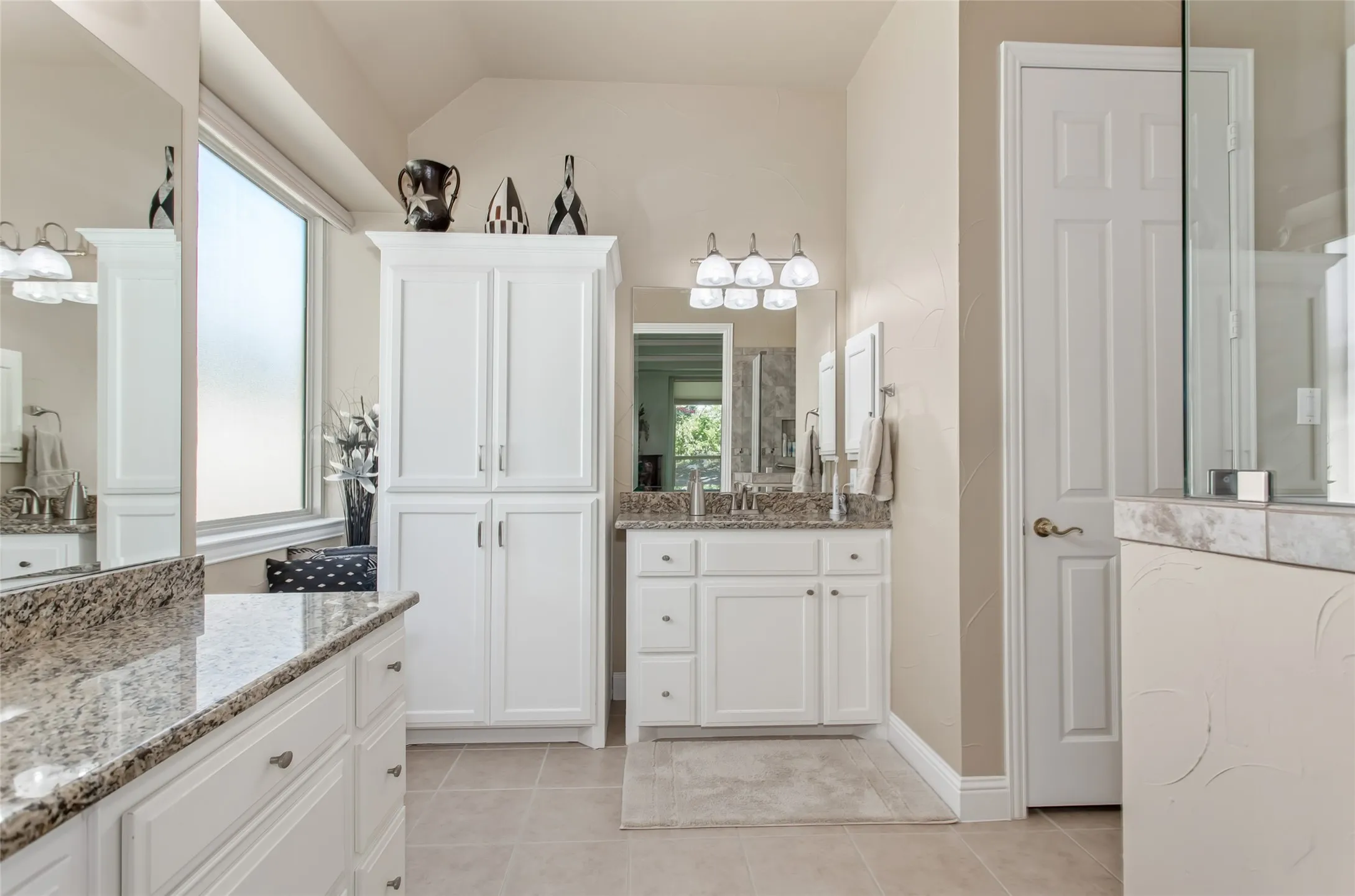 Dual vanity with granite countertops, white cabinetry, a built-in storage cabinet, and a tiled floor