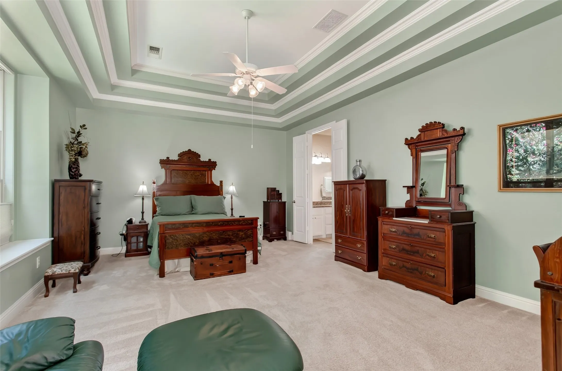 Recessed tray ceiling with decorative molding, ceiling fan, and light-colored carpeting