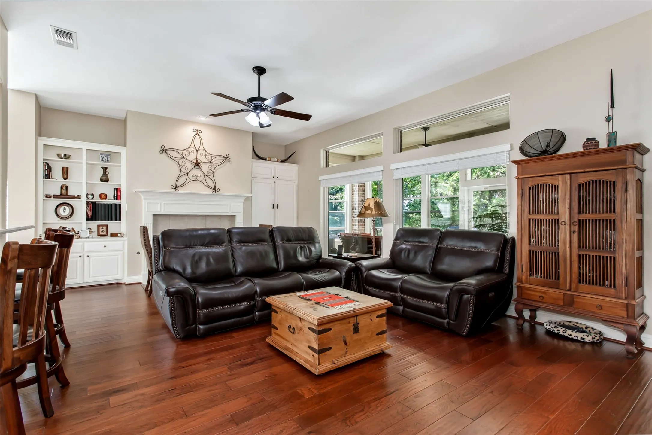 Hardwood flooring, built-in shelving, vaulted ceilings, a fireplace with a mantel, and transom windows